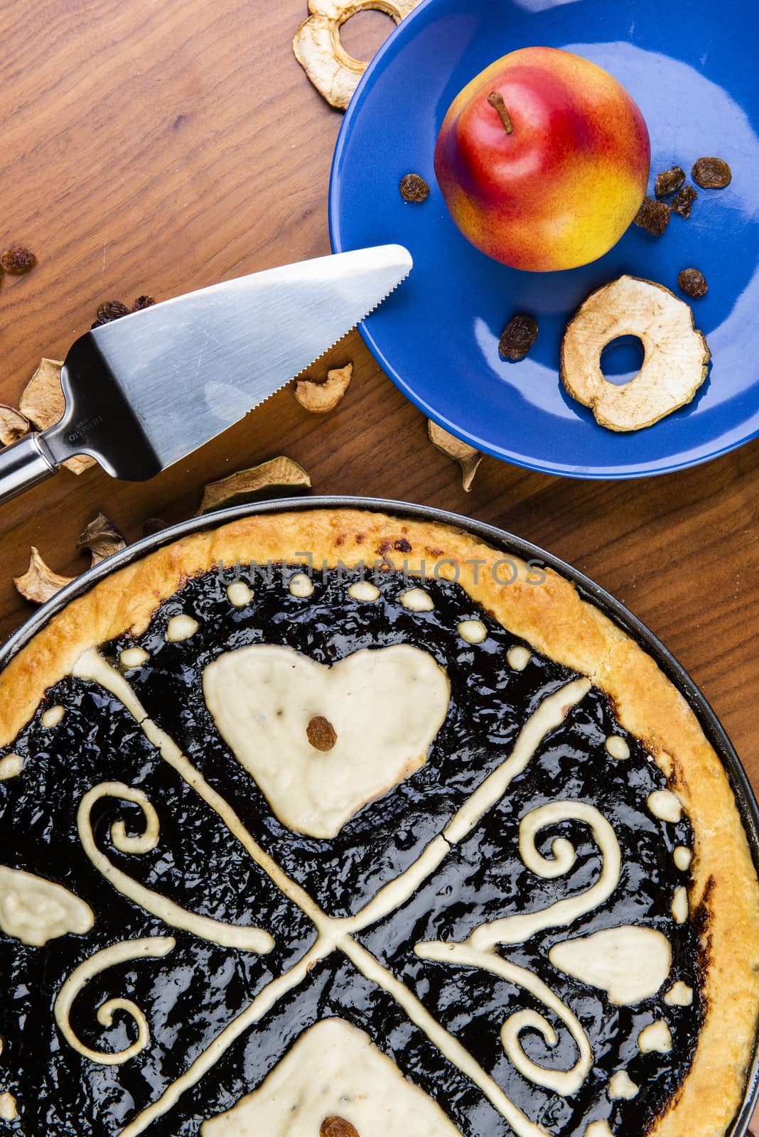 Czech traditional hand and home made round pie Chodsky kolac - speciality of Chodsko region. This one has heart made of quark surounded by plum jam filling. Still life with nuts and fruits on a wooden table