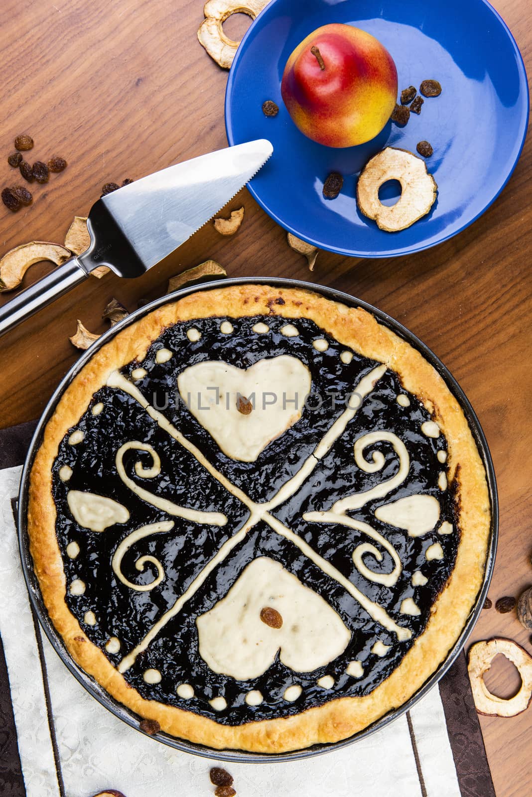 Czech traditional hand and home made round pie Chodsky kolac - speciality of Chodsko region. This one has heart made of quark surounded by plum jam filling. Still life with nuts and fruits on a wooden table