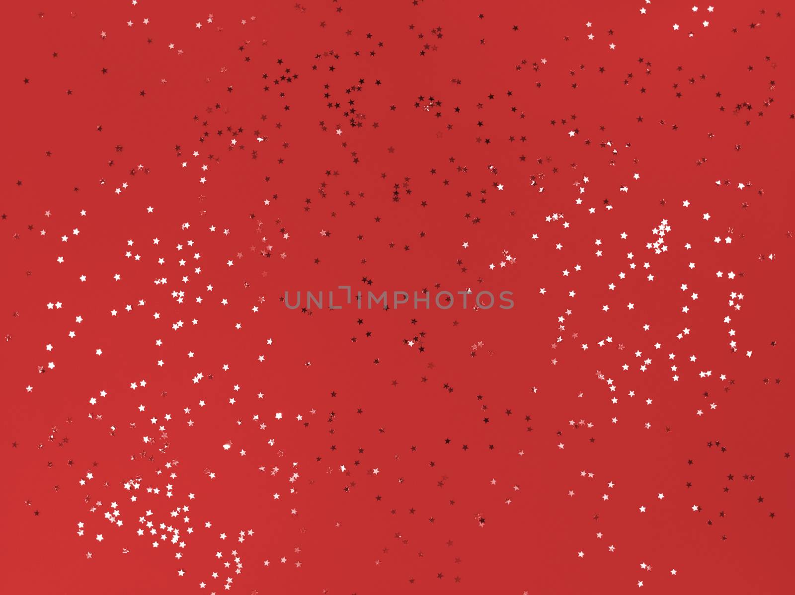 Confetti stars on red paper. Festive background.