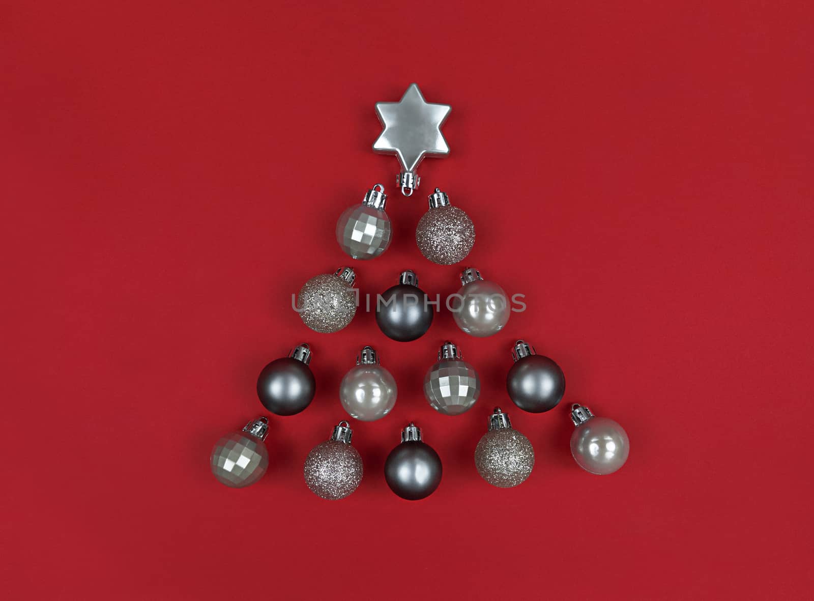 Christmas tree shape made with decor baubles on red paper.