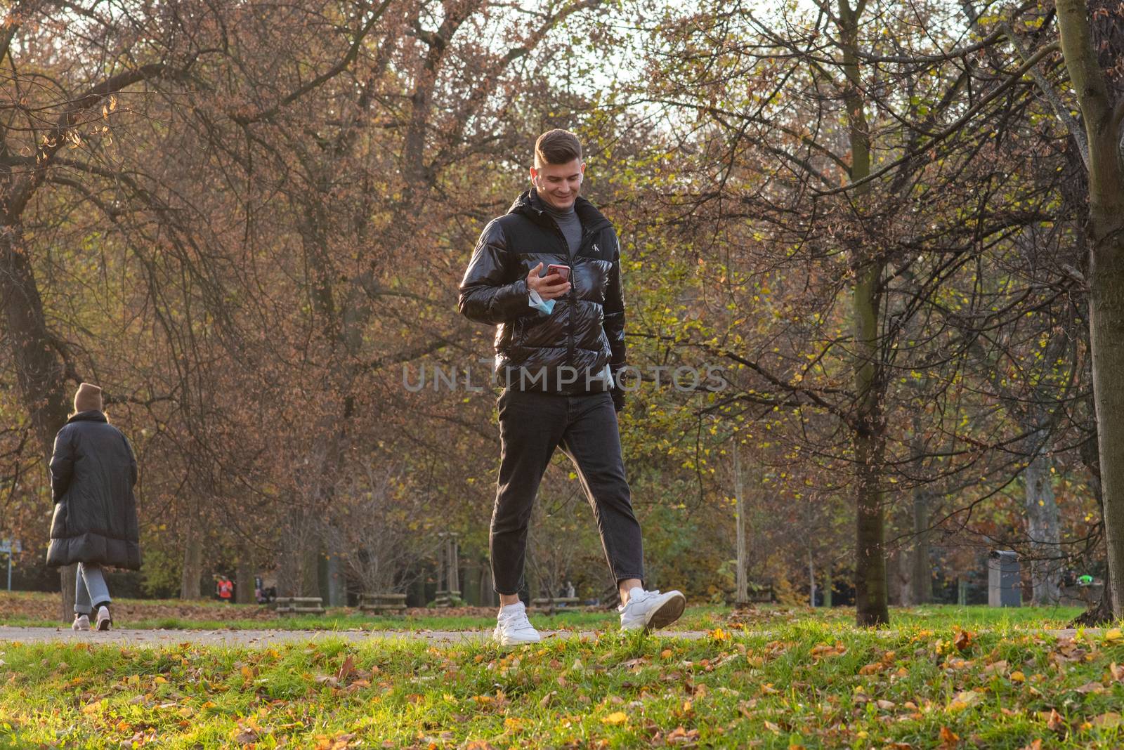 1/14/2020. Park Stromovka. Prague czech Republic. A man is watching or speaking with his phone while walking in the park on a Sunday winter day.