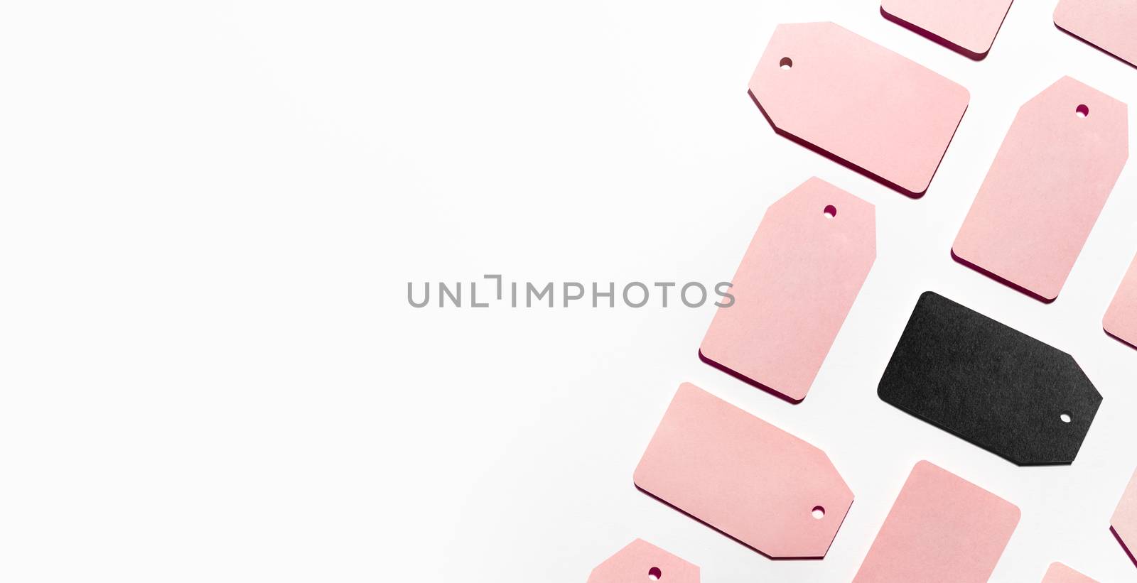 Top view on pattern of many pink and one black clothes tags on white background. Glamorous labels with copy space. Symbol of black Friday sale and shopping. Flat lay.