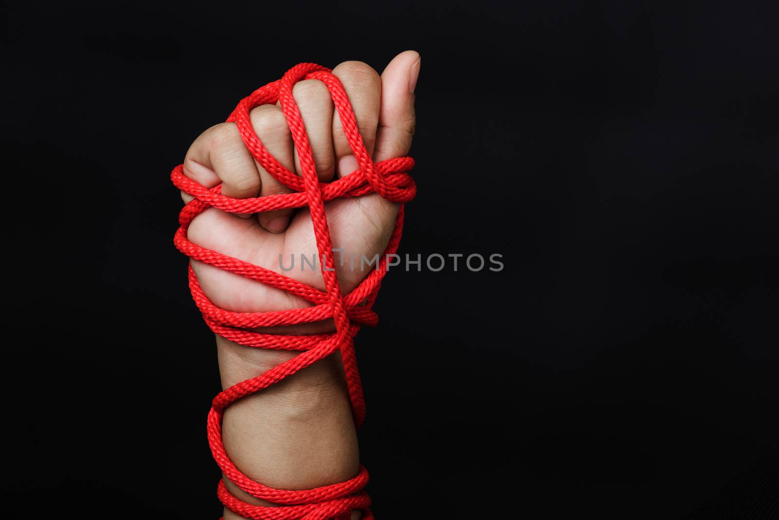 Woman hand tied up with rope on black background, Human trafficking and abuse, International Human Rights day