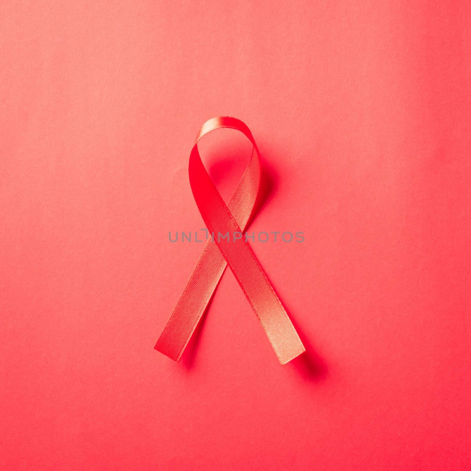 Red bow ribbon symbol HIV, AIDS cancer awareness with shadows, studio shot isolated on red background, Healthcare medicine concept, World AIDS Day