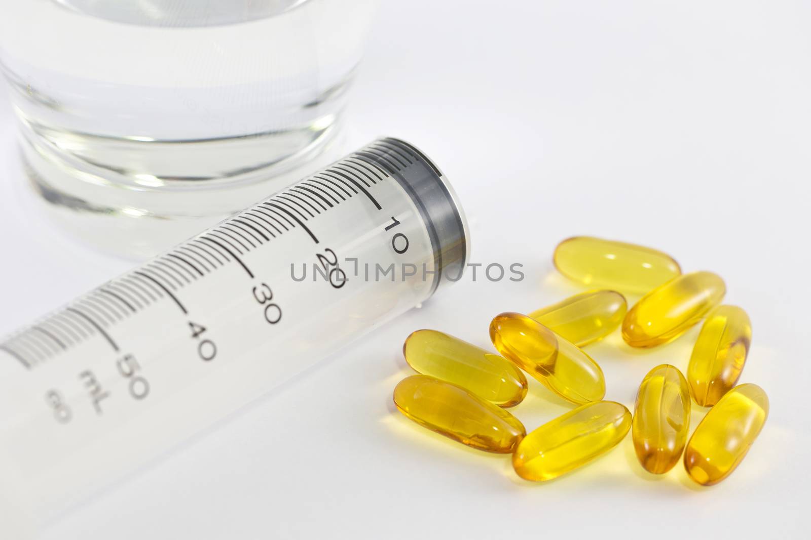 Vitamin capsules and syringe isolated white background.
