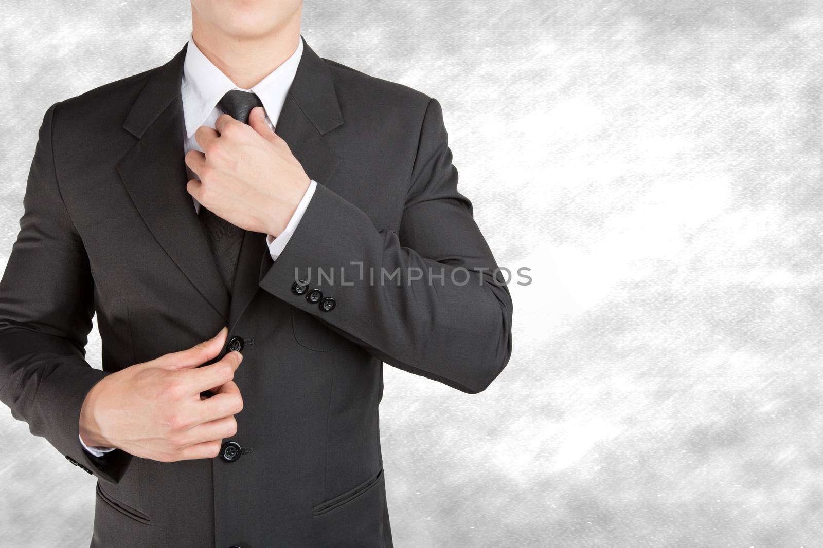 Well dressed businessman looklike smart adjusting  his neck tie  by jayzynism