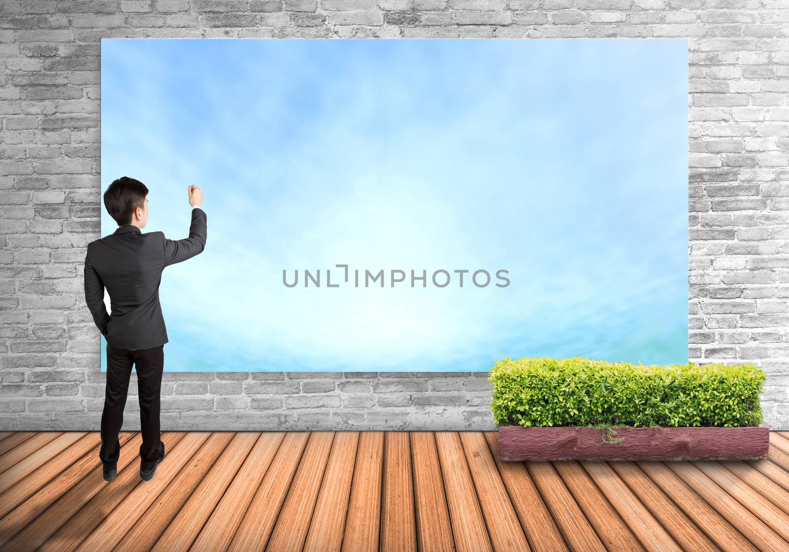 Businessman writing on sky board imagine the future, isolated on wall background.