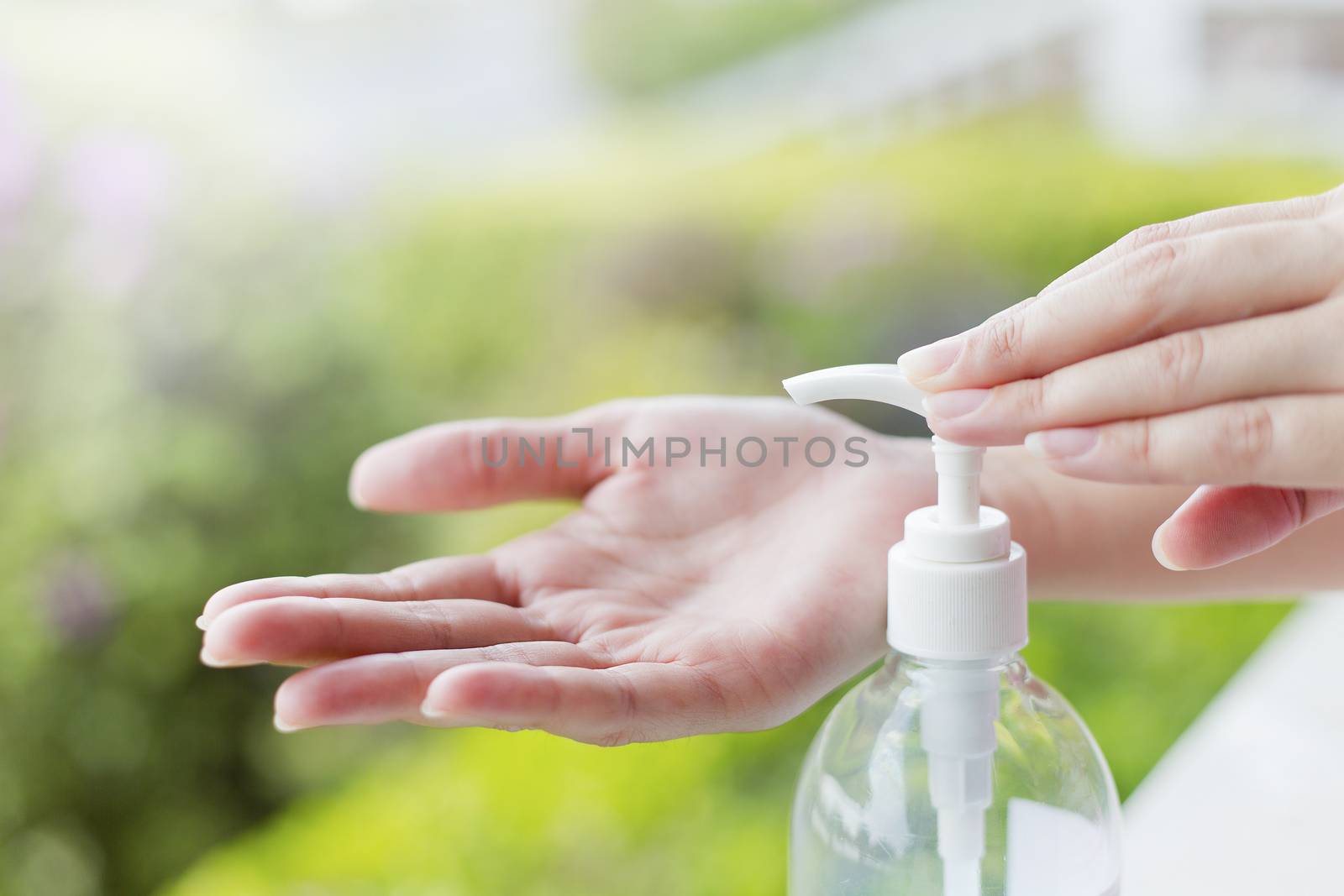 Female hands using wash hand sanitizer gel pump dispenser. by jayzynism