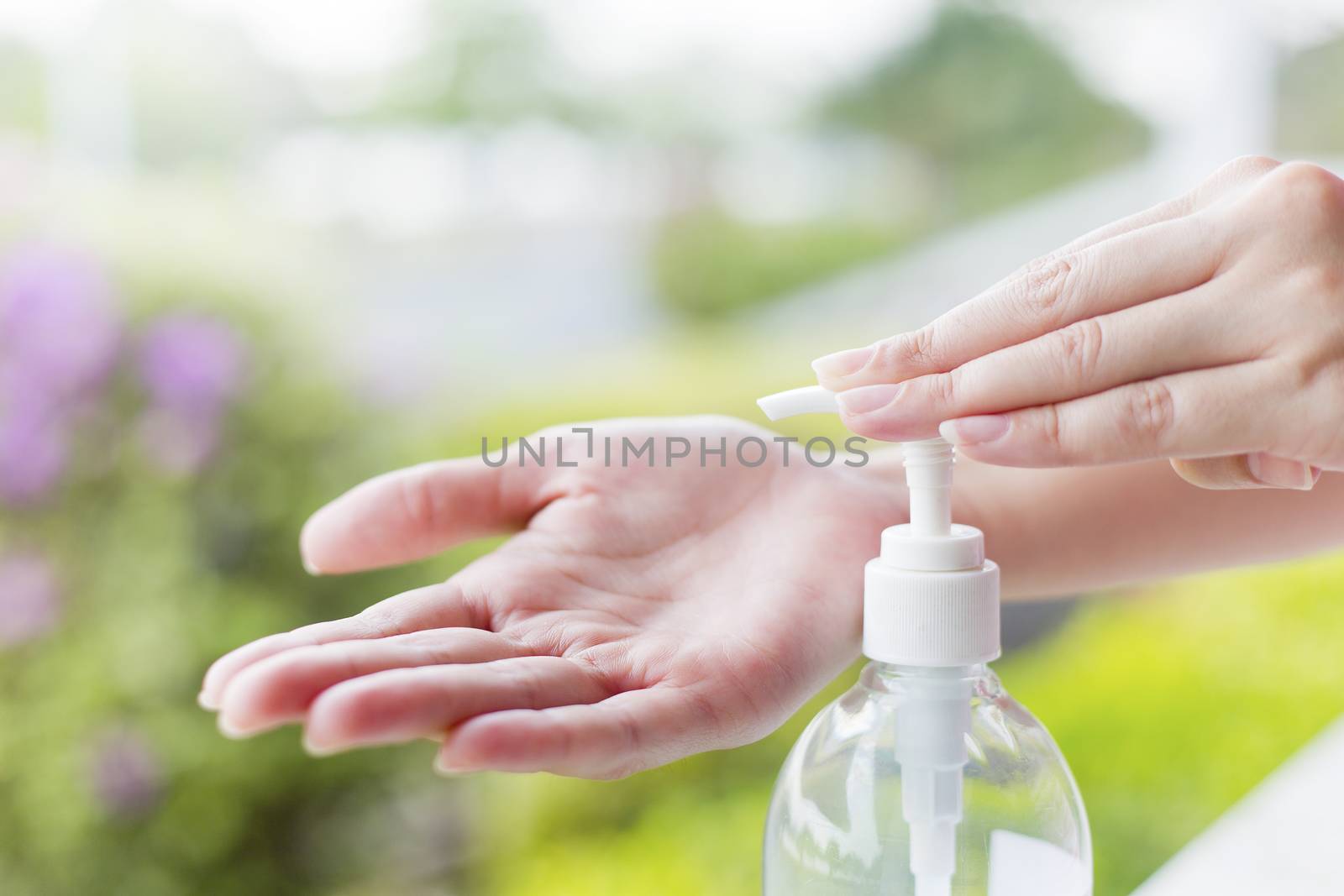 Female hands using wash hand sanitizer gel pump dispenser. by jayzynism