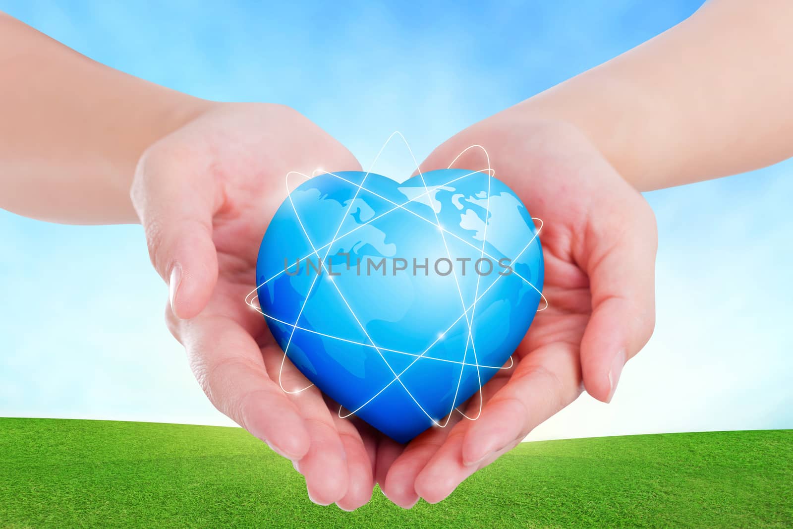 Female hands holding on earth global heart on grassland.