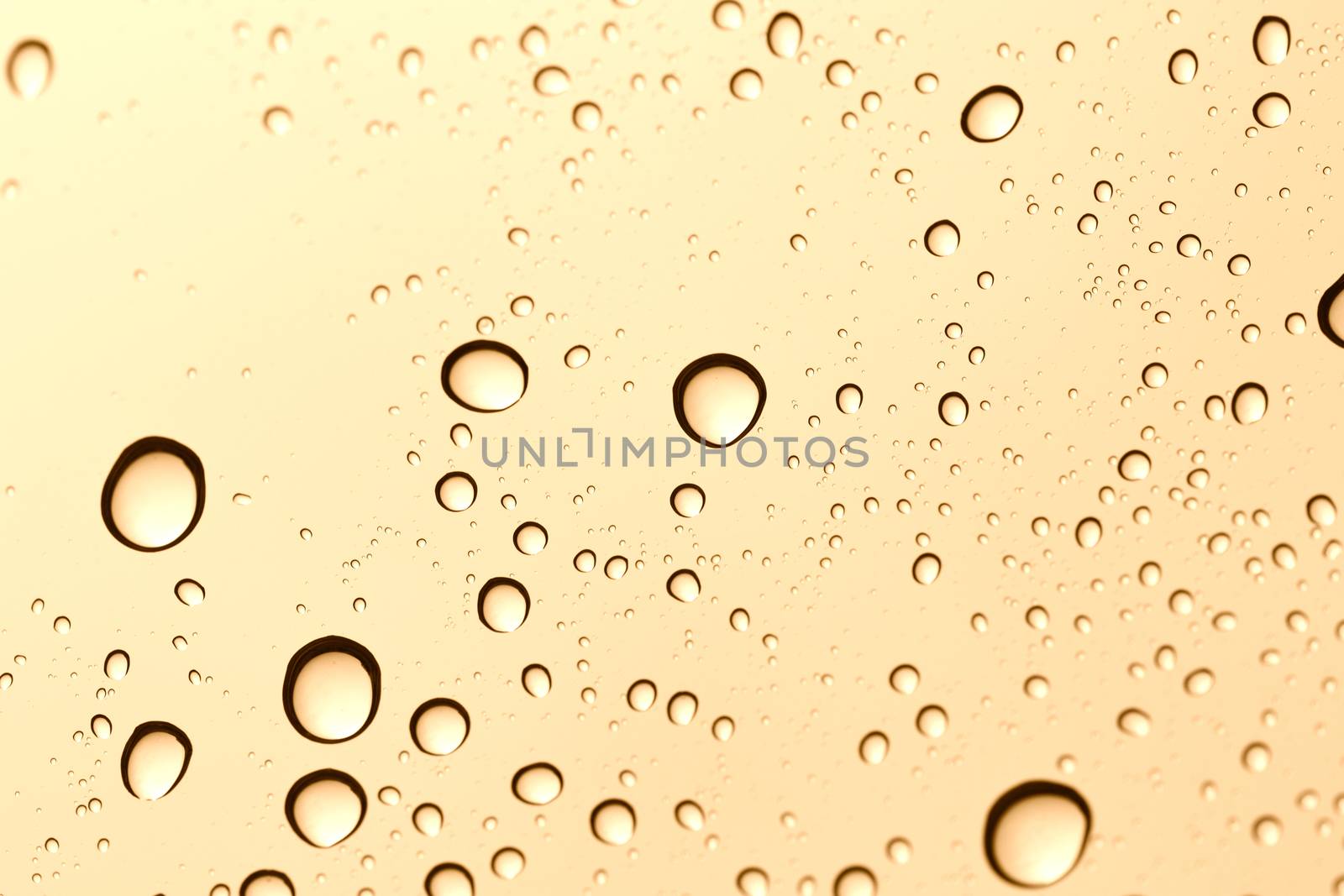 Gold water drop on glass mirror background.