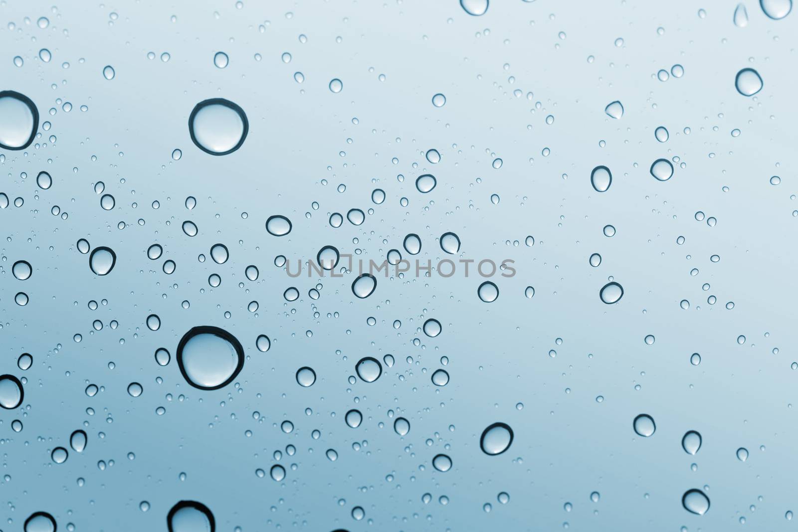 Water drop blue sky on glass mirror background.