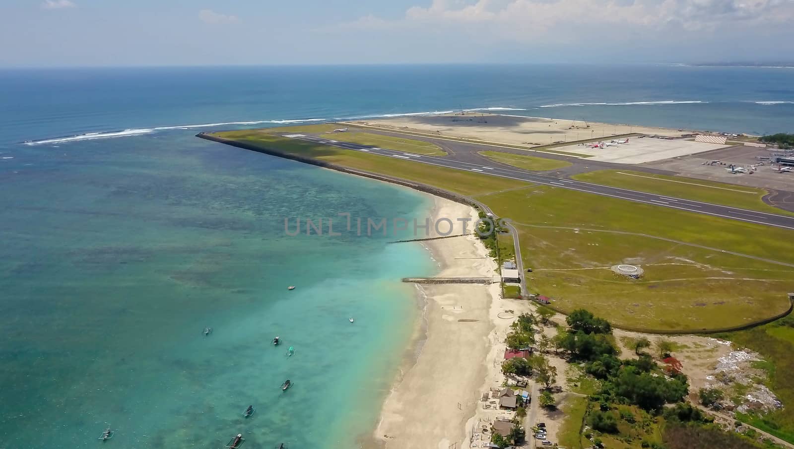 Aerial view of the runway from the top of the tower of the international airport controls Bali with a parked plane and several planes are on the runway. Aerial view to Ngurah Rai airport, Indonesia.