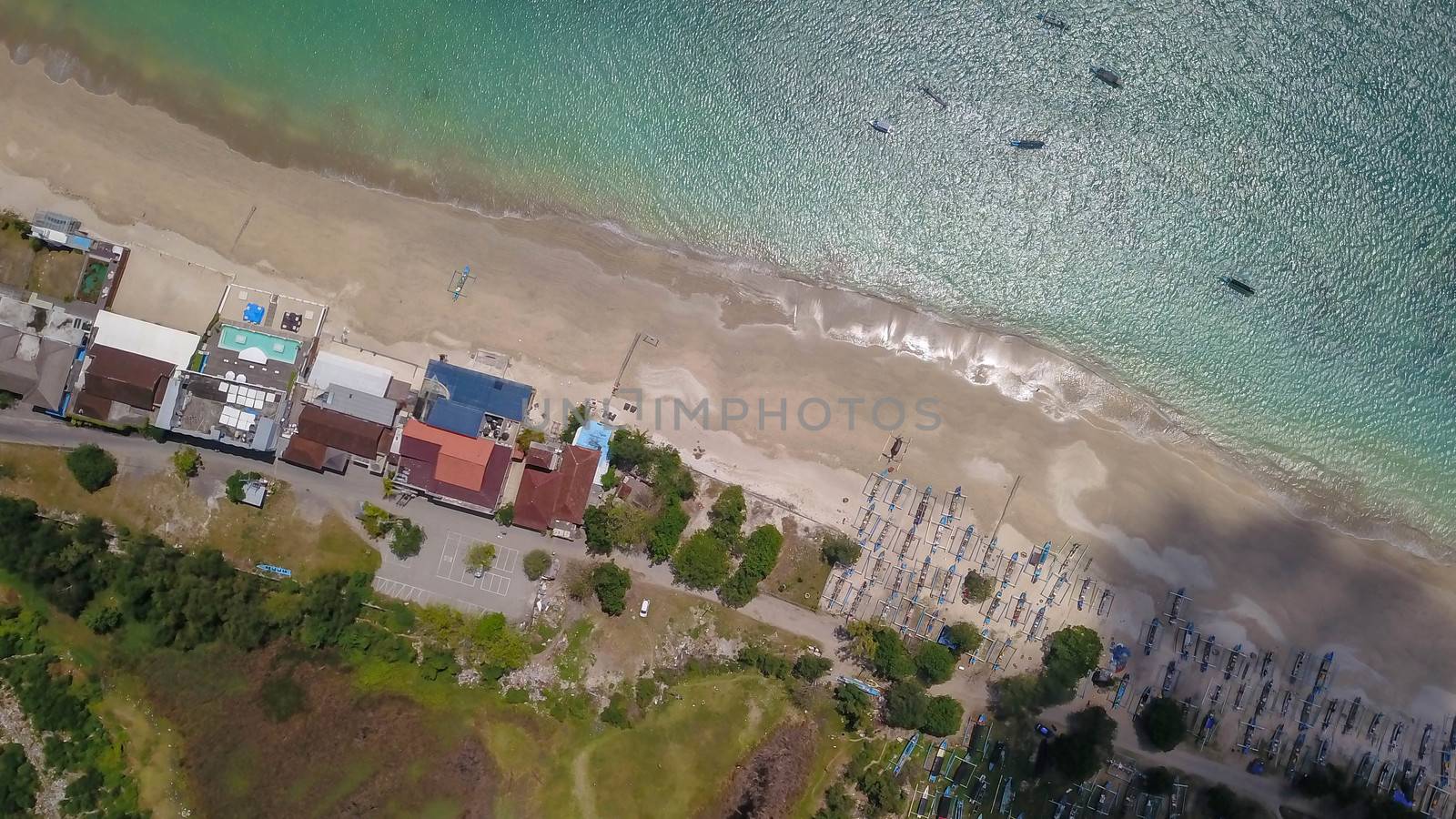 Aerial drone view of Holiday In Sanur Beach, Bali, Indonesia with ocean, boats, beach, villas, and people