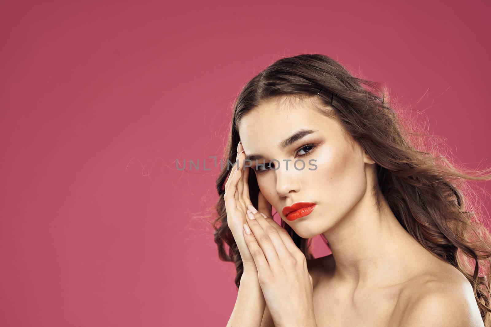 Beautiful brunette woman with makeup on her face on a pink background naked shoulders by SHOTPRIME