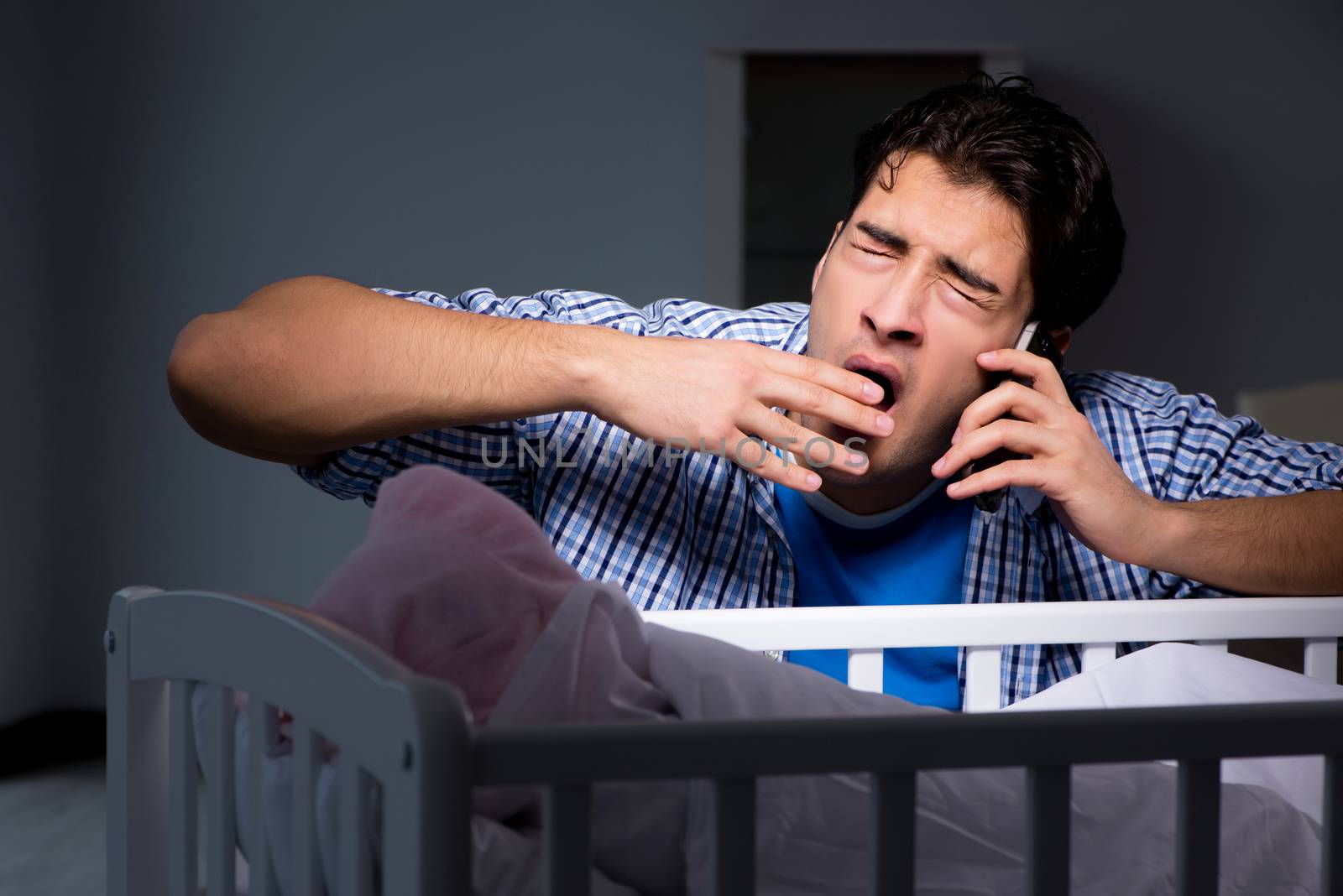 Young father dad sleeping while looking after newborn baby