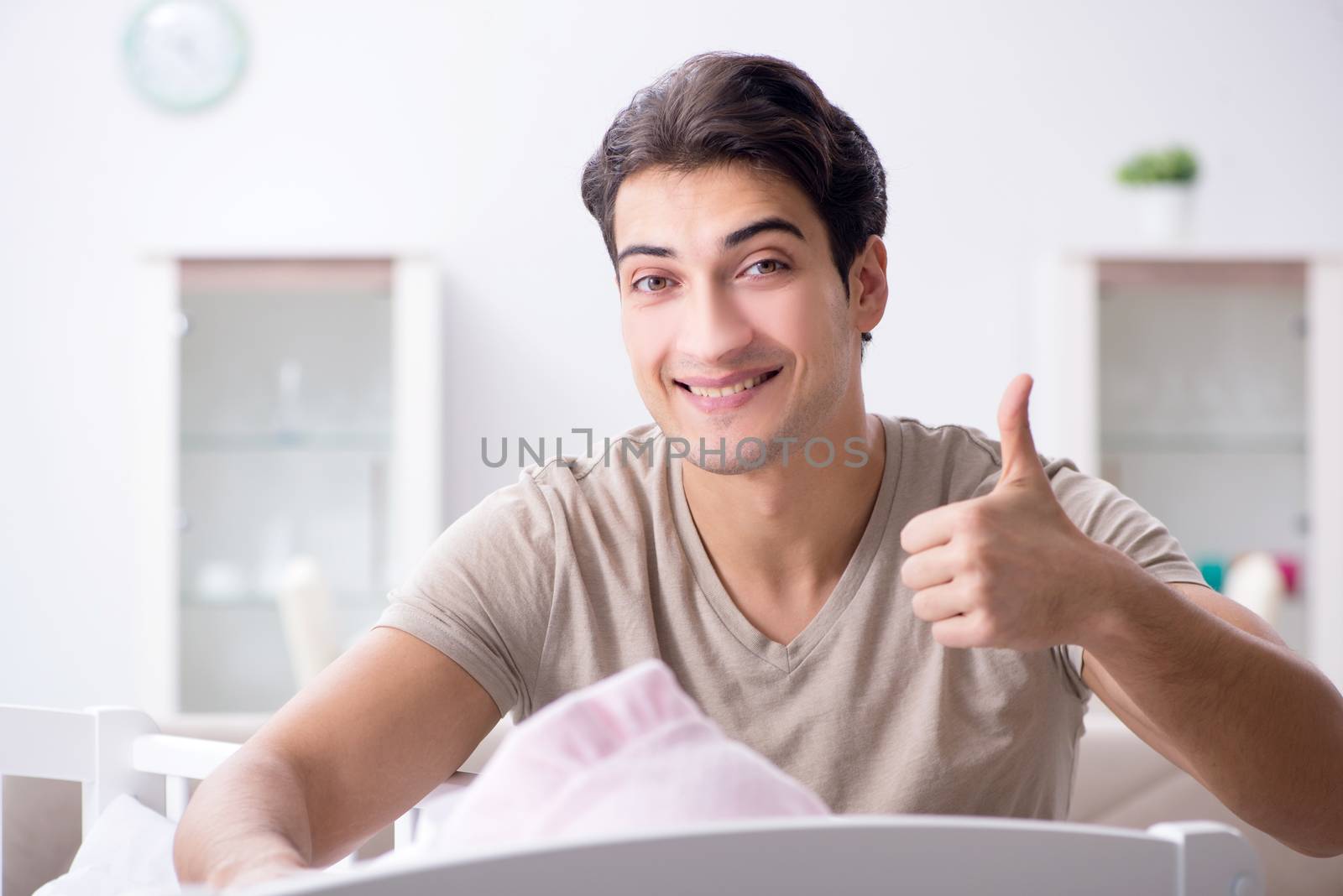 Young father enjoying time with newborn baby at home