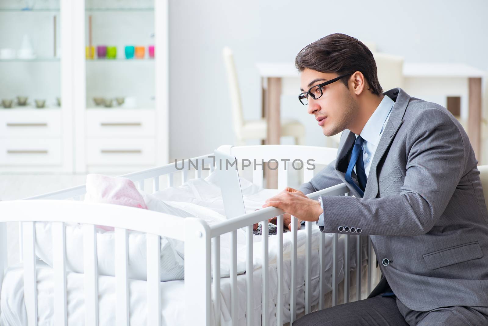 Young businessman trying to work from home caring after newborn baby