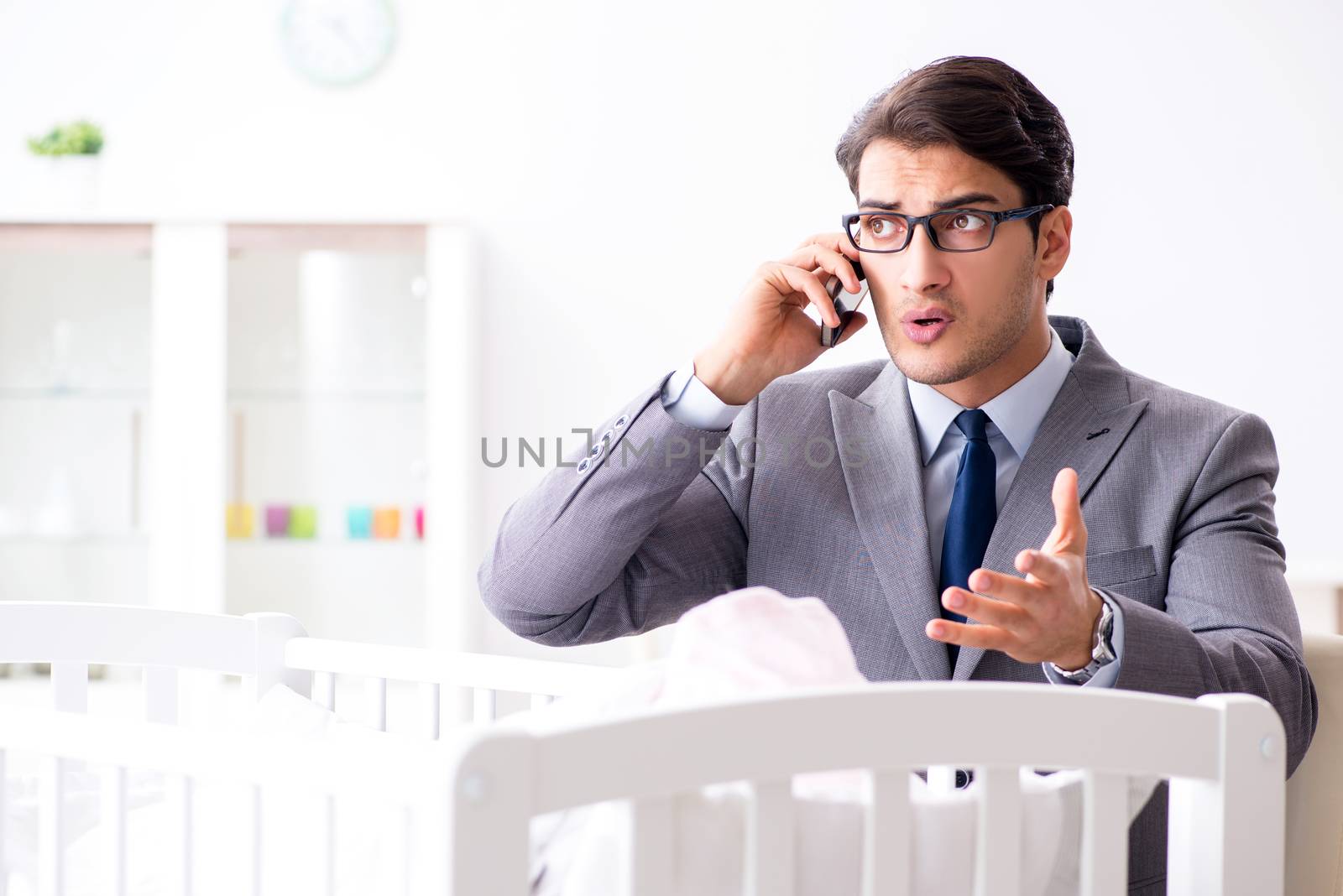 Young businessman trying to work from home caring after newborn baby