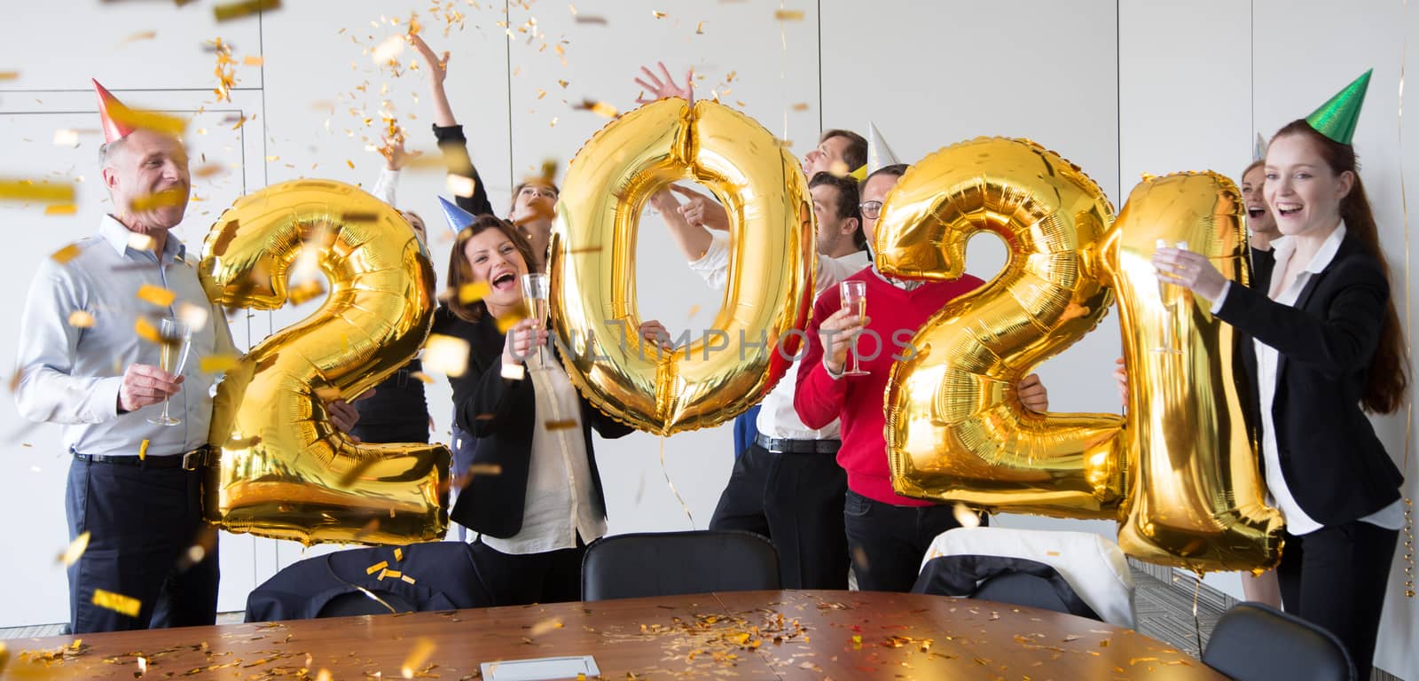 Business people are celebrating holiday in modern office drinking champagne and having fun in coworking. Merry Christmas and Happy New Year 2021. Balloon numbers