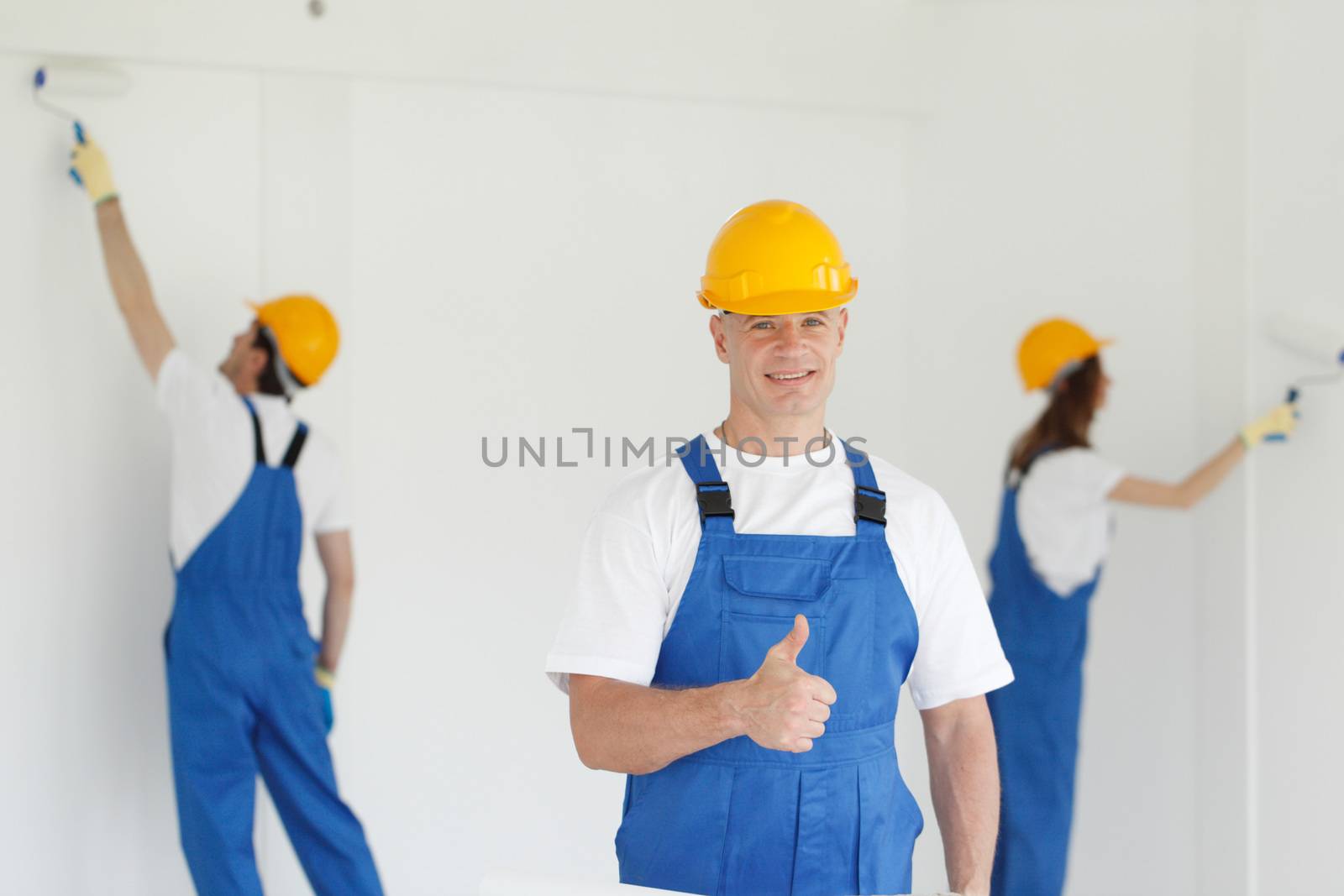 Workman gives thumbs up in front of two painters