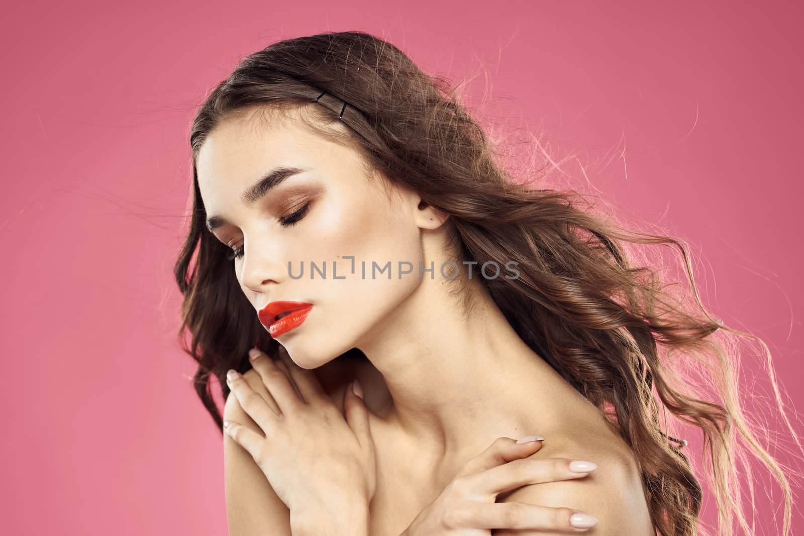 Beautiful woman with red lips on a pink background nude shoulders cropped view. High quality photo