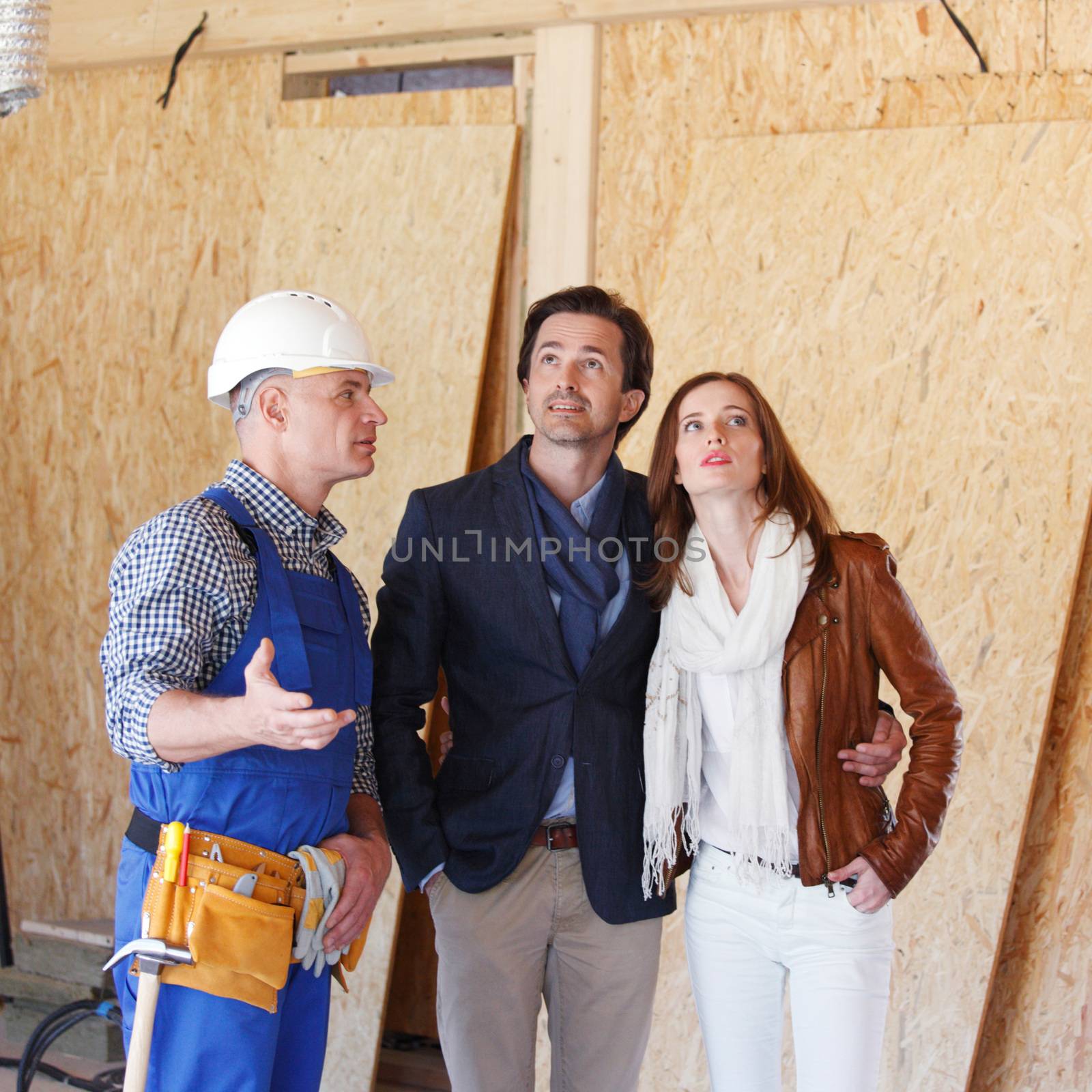 Foreman or achitect engineer shows future house to happy couple