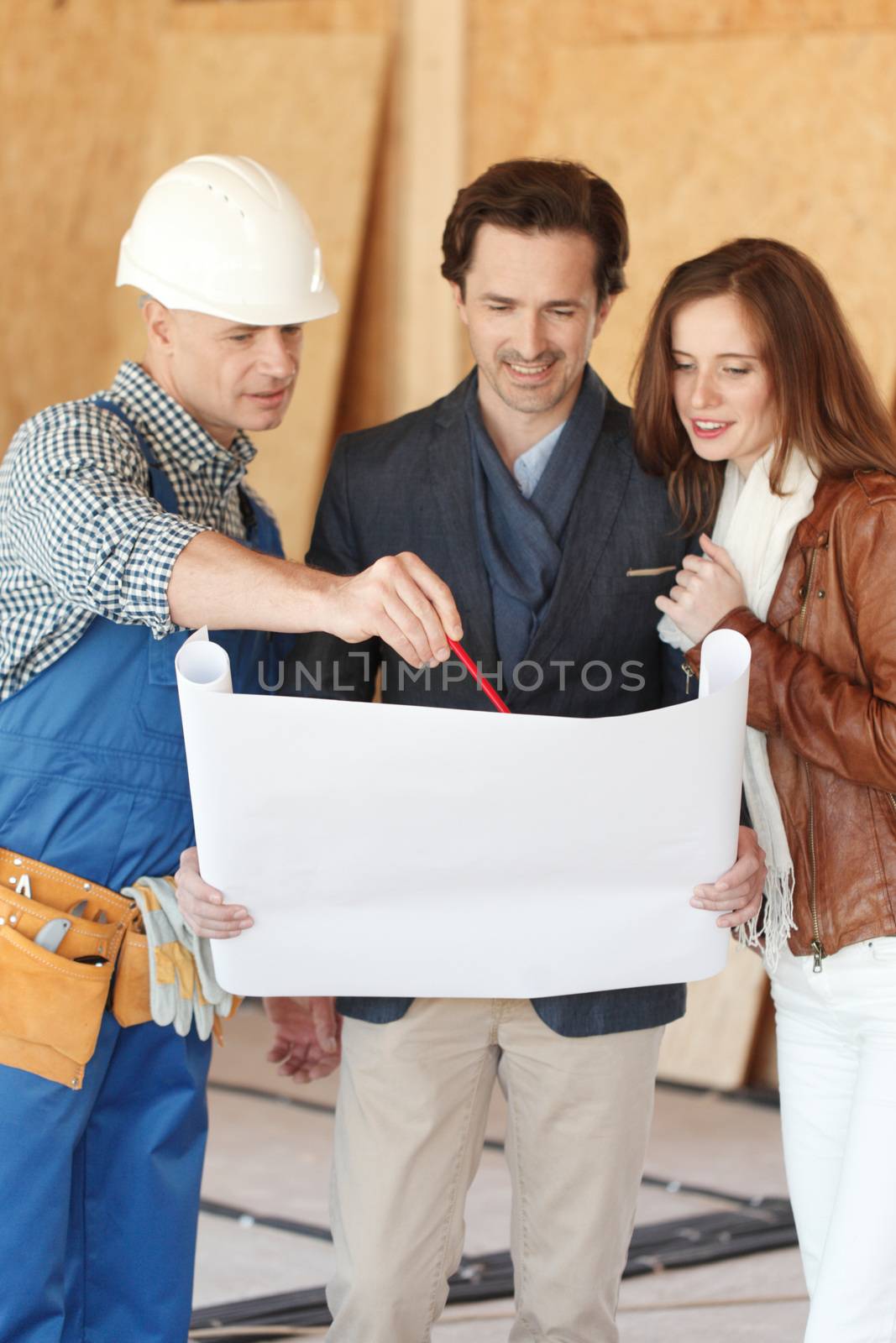 Foreman showing house design construction plan to a happy young couple new house real estate concept