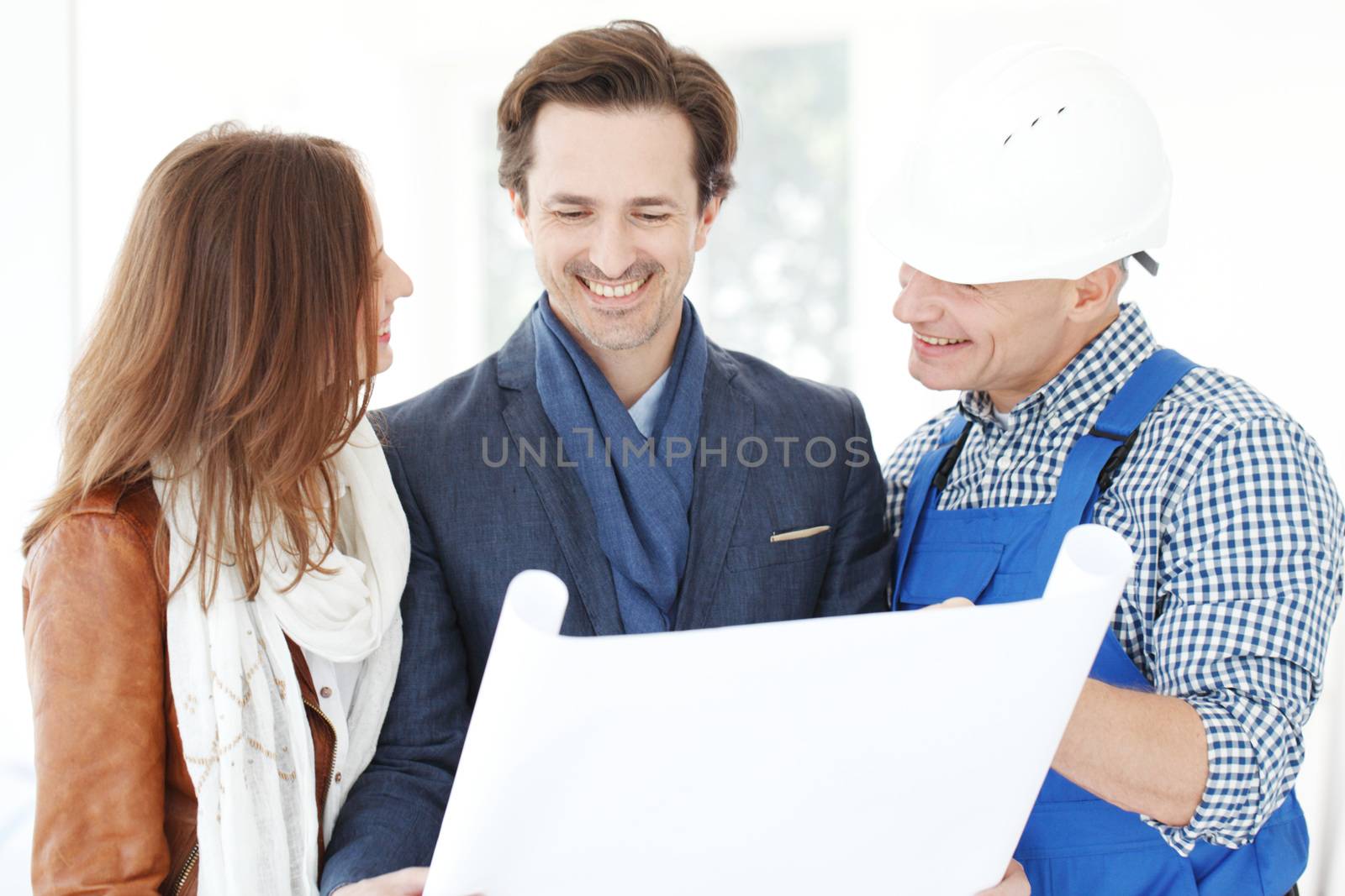 Foreman showing house design construction plan to a happy young couple new house real estate concept