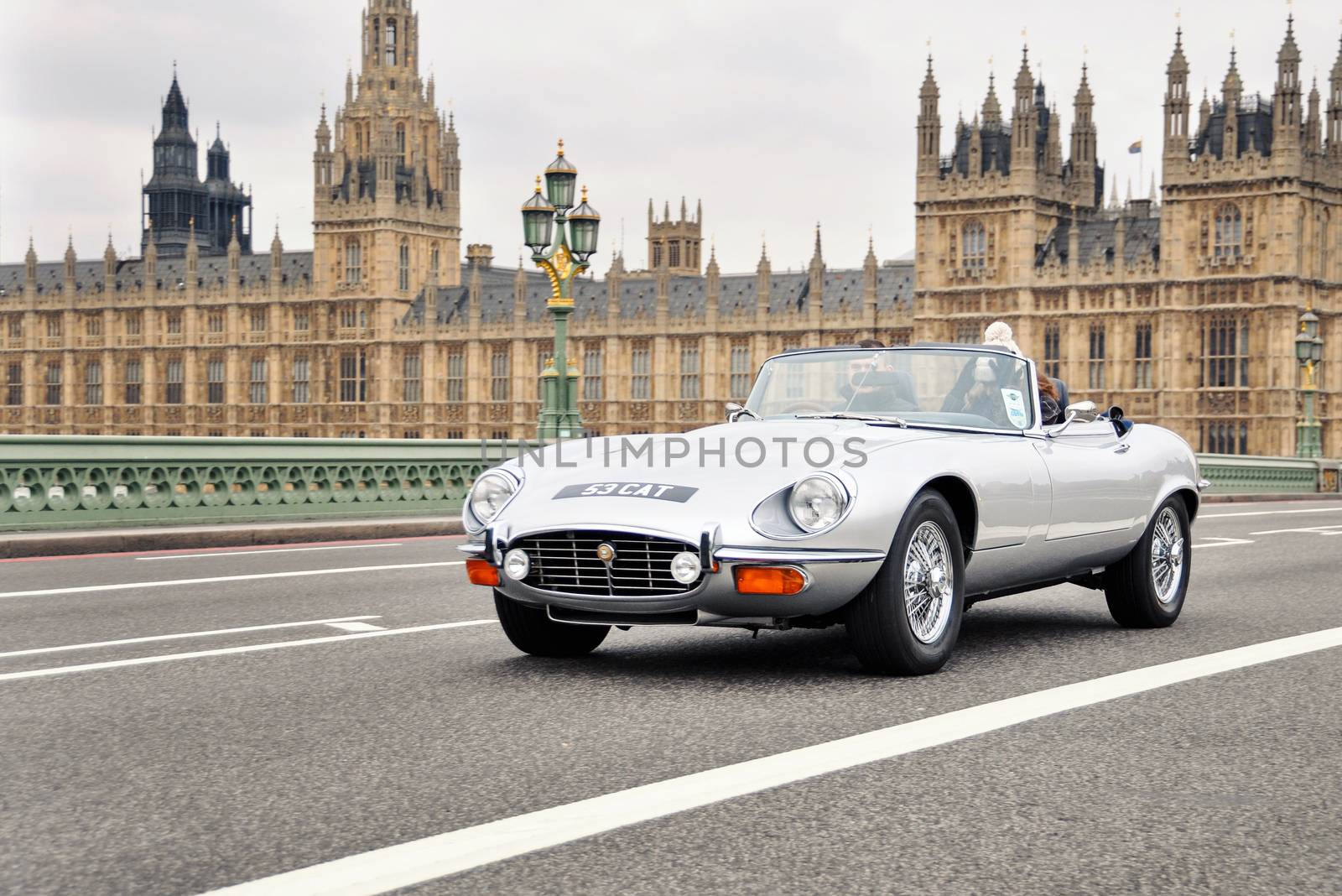 LONDON, UK - CIRCA NOVEMBER 2011: A silver Jaguar E-Type on Westminster Bridge with the Palace of Westminster in the background.