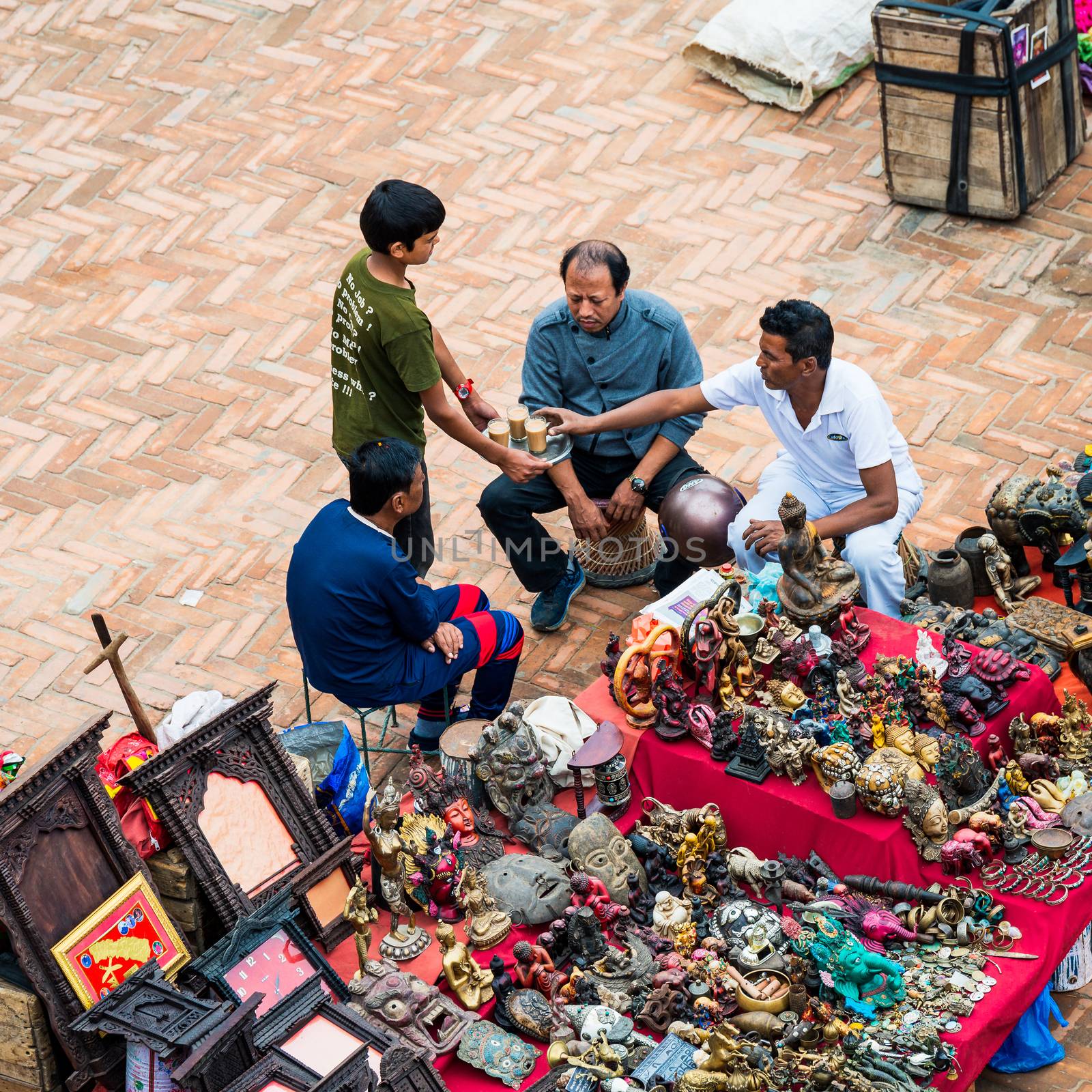 KATHMANDU, NEPAL - CIRCA APRIL 2018: A boy serves tea to souvenir sellers at Kathmandu Durbar Square.