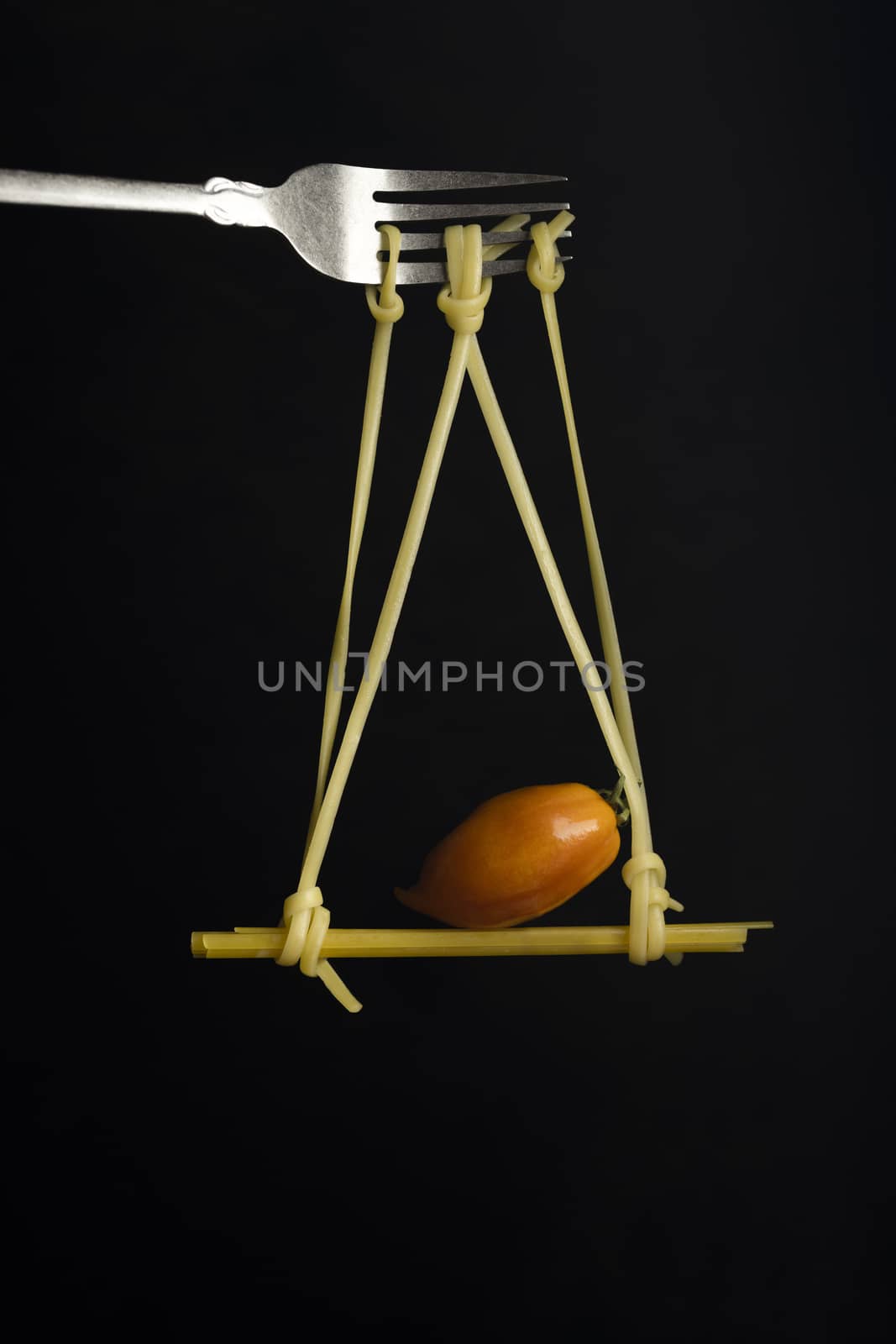 Spaghetti on a fork in front of black background. Swing from spaghetti by sashokddt