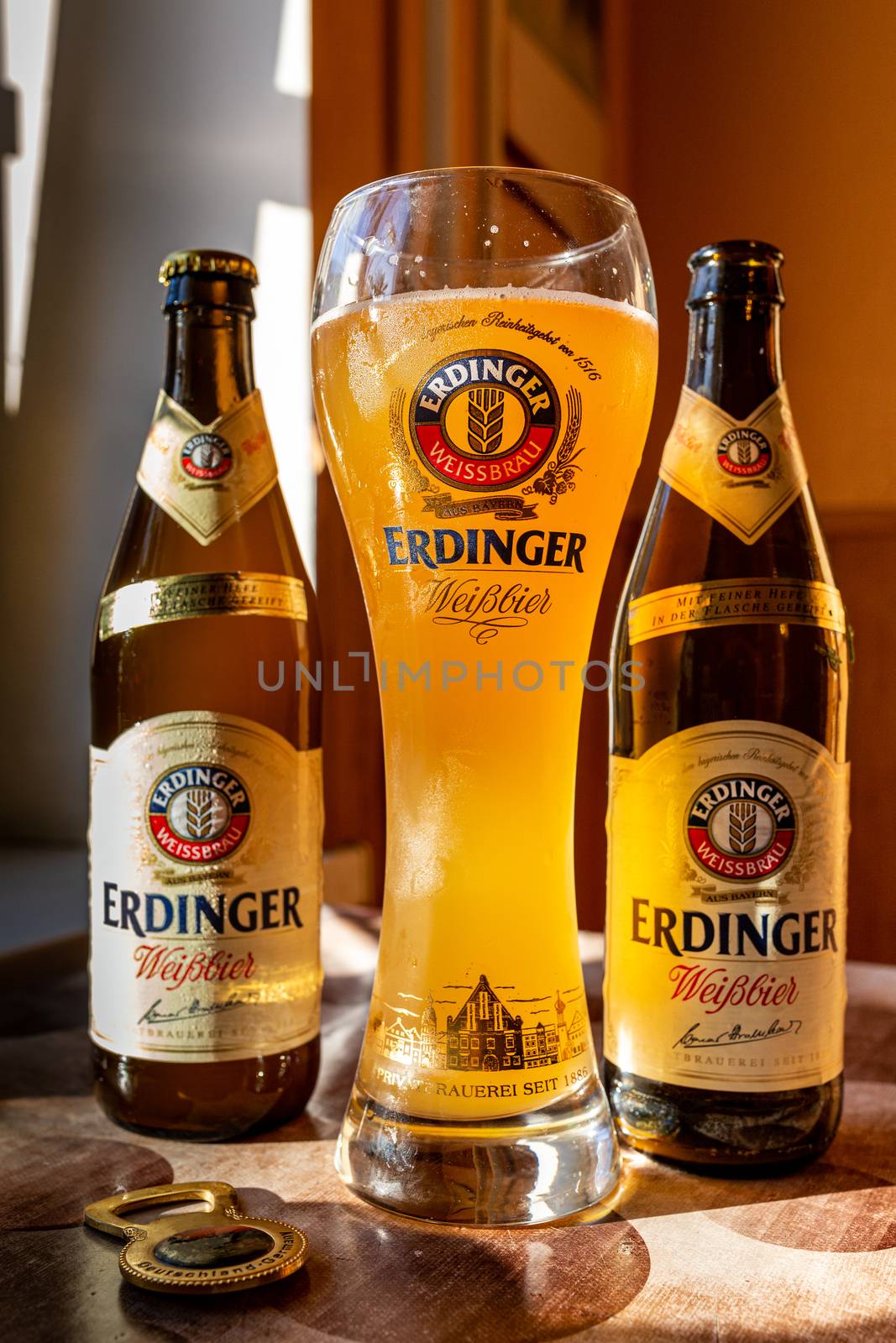Erdinger beer is poured in a branded beer glass and two bottles by 977_ReX_977