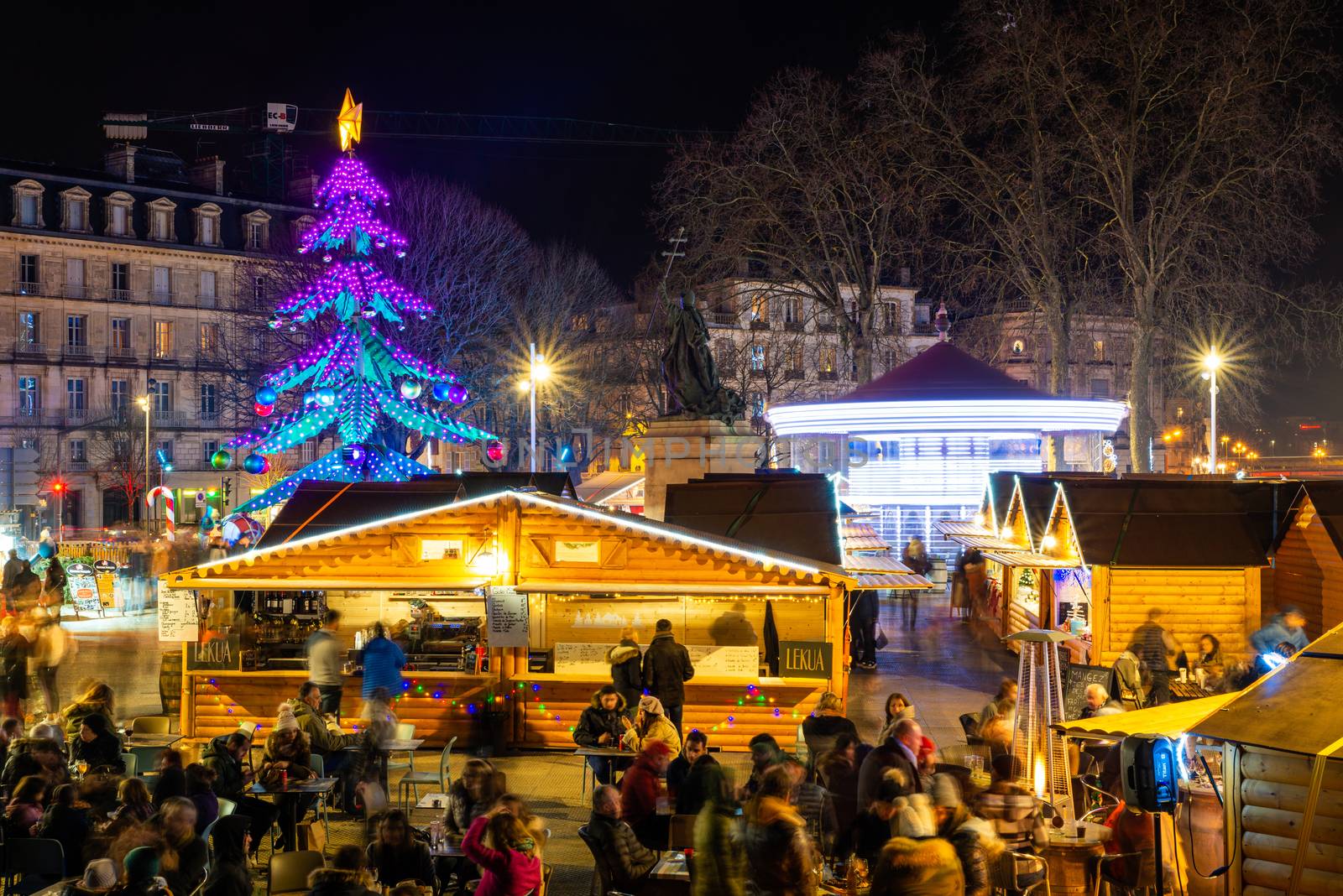 BAYONNE, FRANCE - DECEMBER 28, 2019: The Christmas market at night with the carousel and a Christmas tree carousel