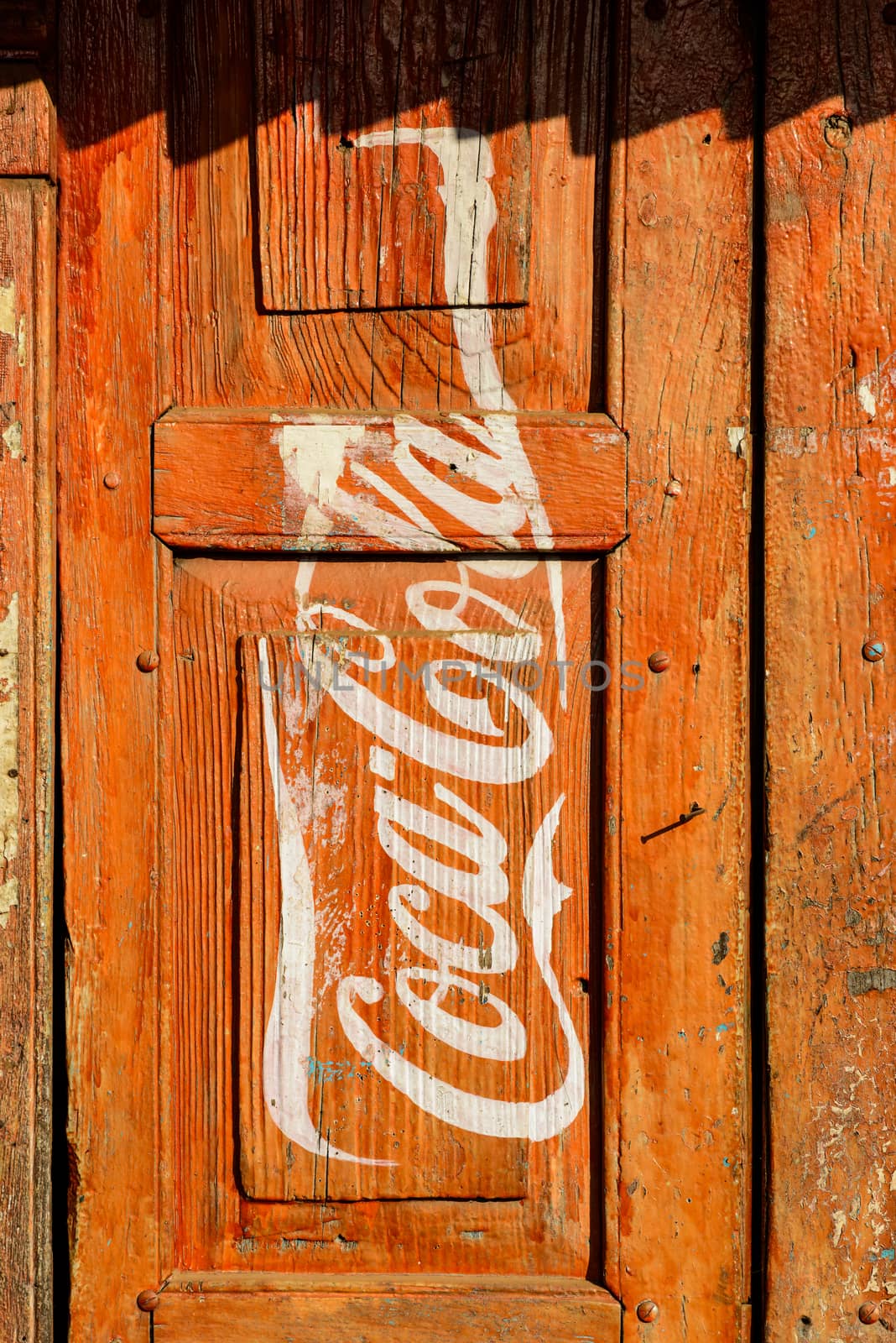 KATHMANDU, NEPAL - CIRCA JANUARY 2014: Vintage Coca-Cola advertisement painted on a red wooden door.