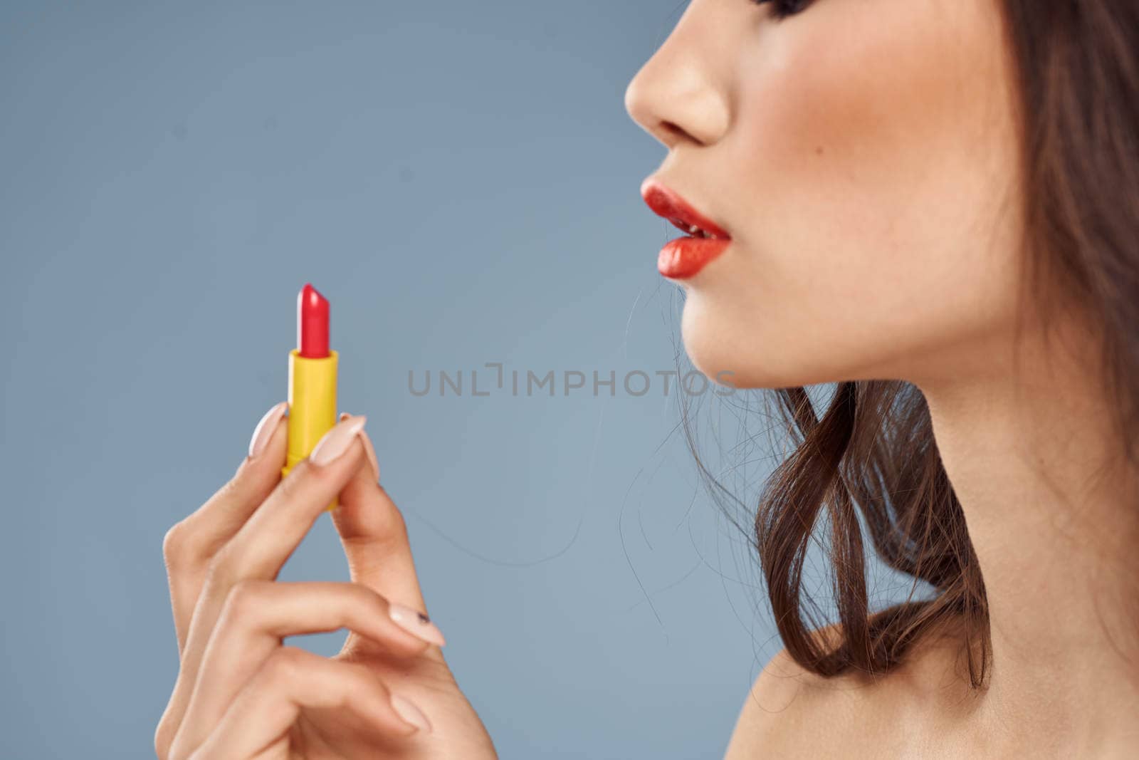 Woman with lipstick on a gray background brunette makeup with eye shadow on the eyelids. High quality photo