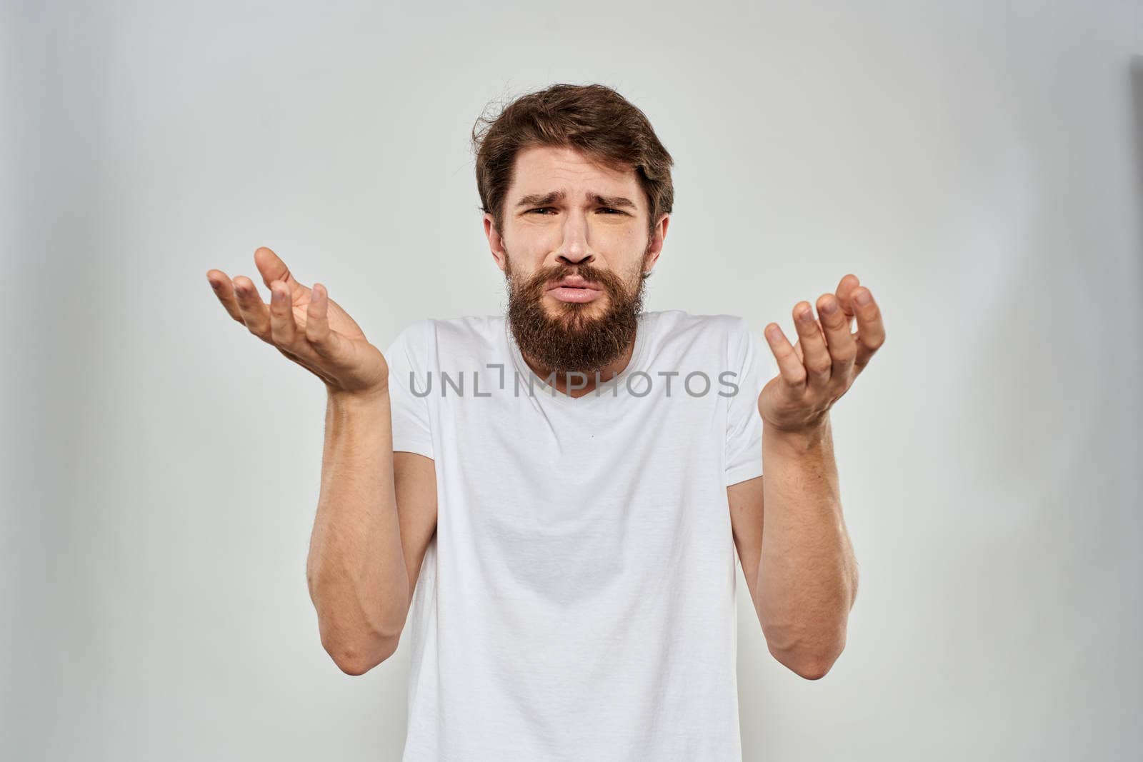 Bearded man gesturing with hand white cropped t-shirt studio lifestyle. High quality photo