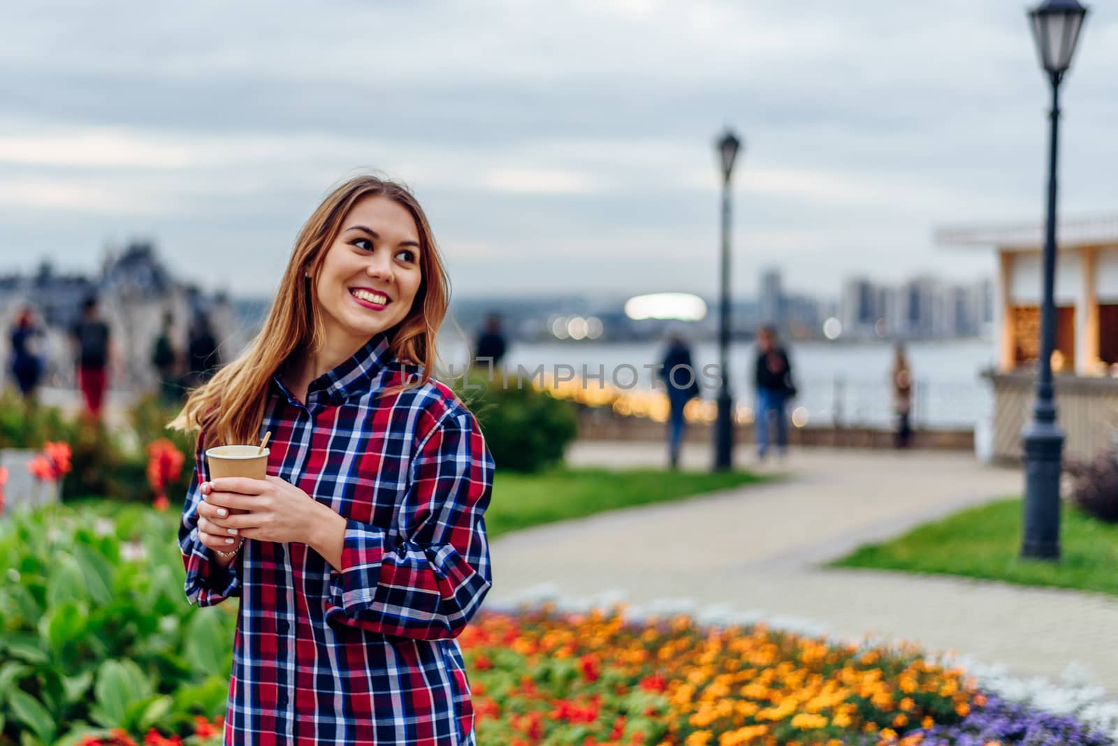 Coffee on the go. Beautiful young woman holding coffee cup and smiling