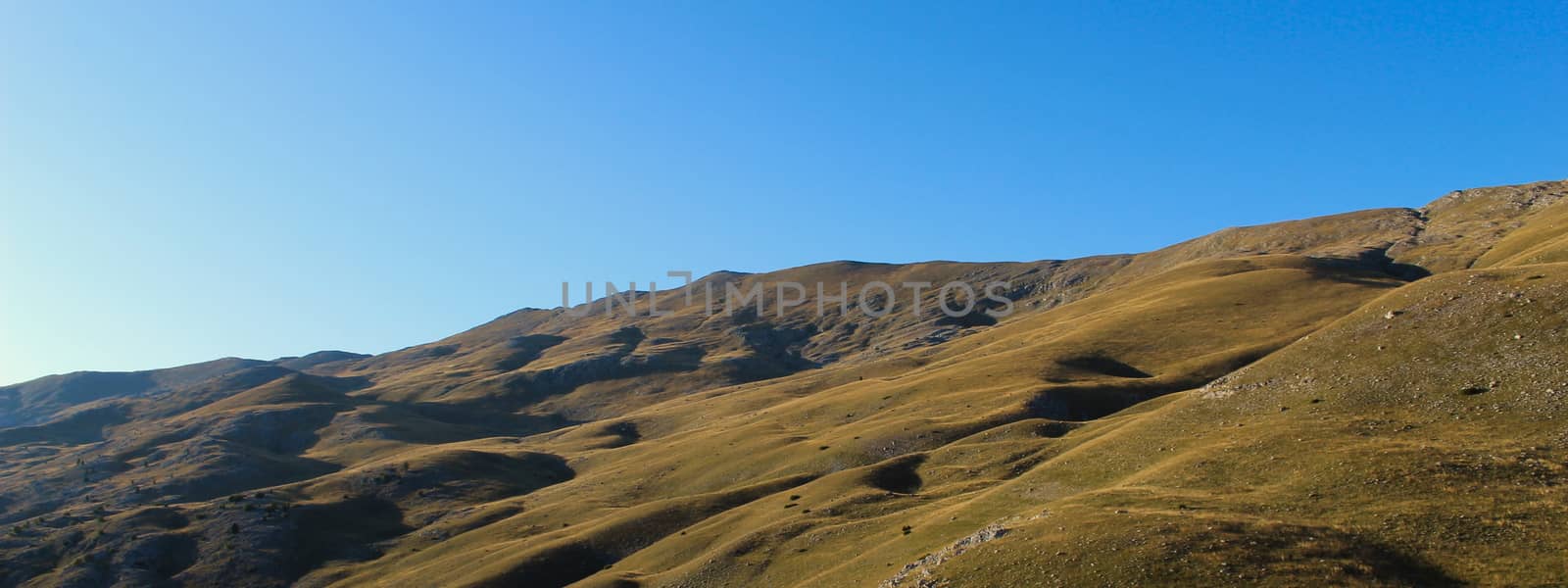 Banner. Mountain in the fall before sunset. Landscape of Bjelasnica mountain, meadows, pastures, grass, stones, sky. Simple but magnificent landscape view. Bjelasnica Mountain, Bosnia and Herzegovina.
