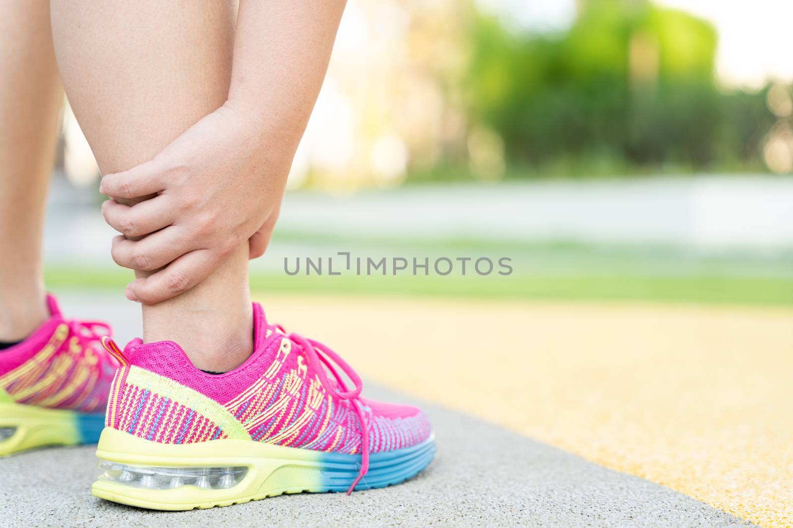 Female fatty runner athlete leg injury and pain. Hands grab painful leg while running in the park. by mikesaran