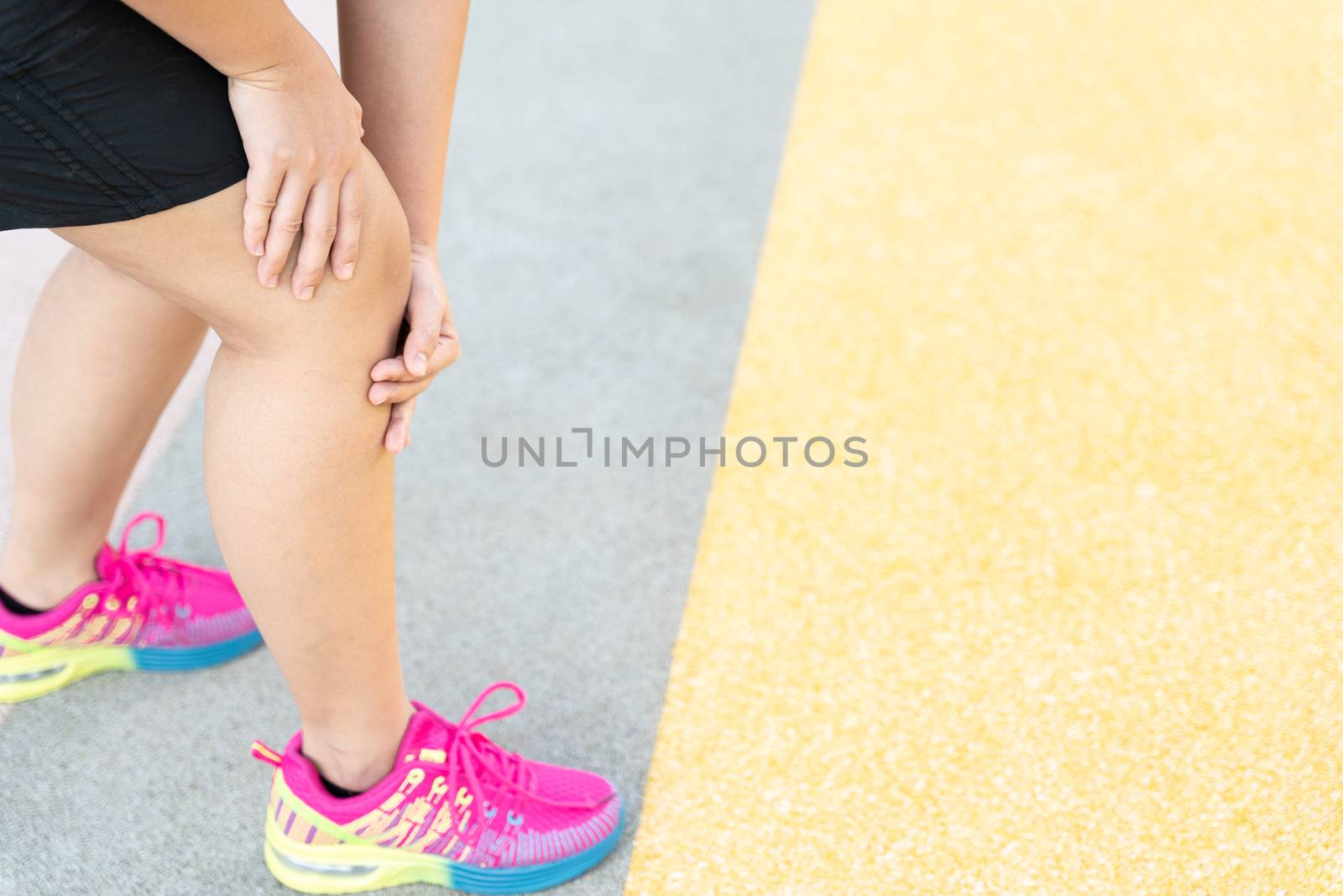 Female fatty runner athlete leg injury and pain. Hands grab painful knee while running in the park. by mikesaran