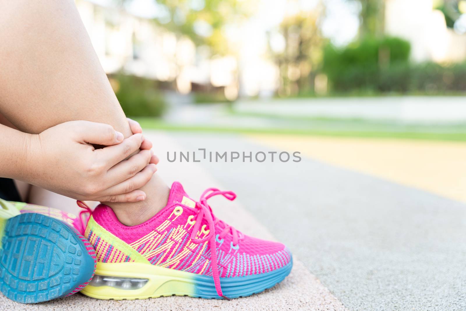 Female fatty runner athlete leg injury and pain. Hands grab painful leg while running in the park.