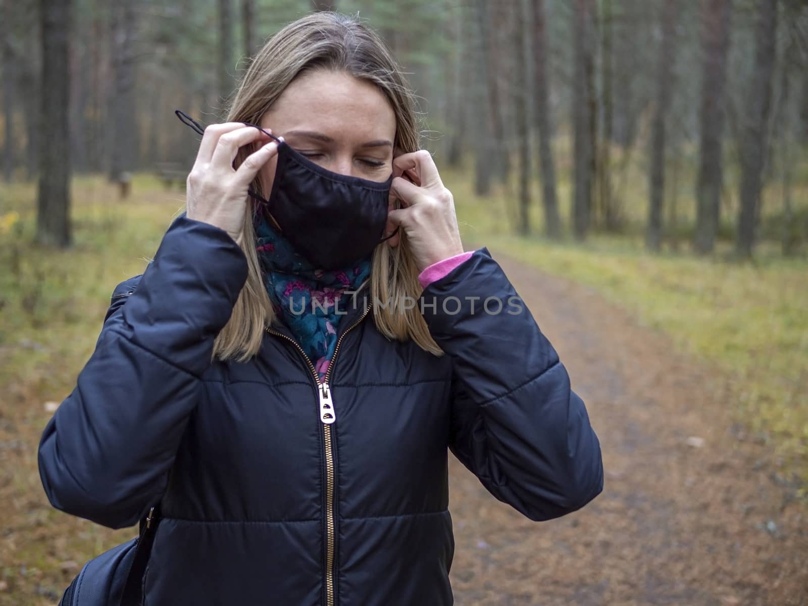 Beautiful european Women Wearing Protective Mask Outside Pretty young girl in medical black face mask in a forest. covid19 concept. modern reality. copy space. 2020, allergy. Autumn season. Copy space