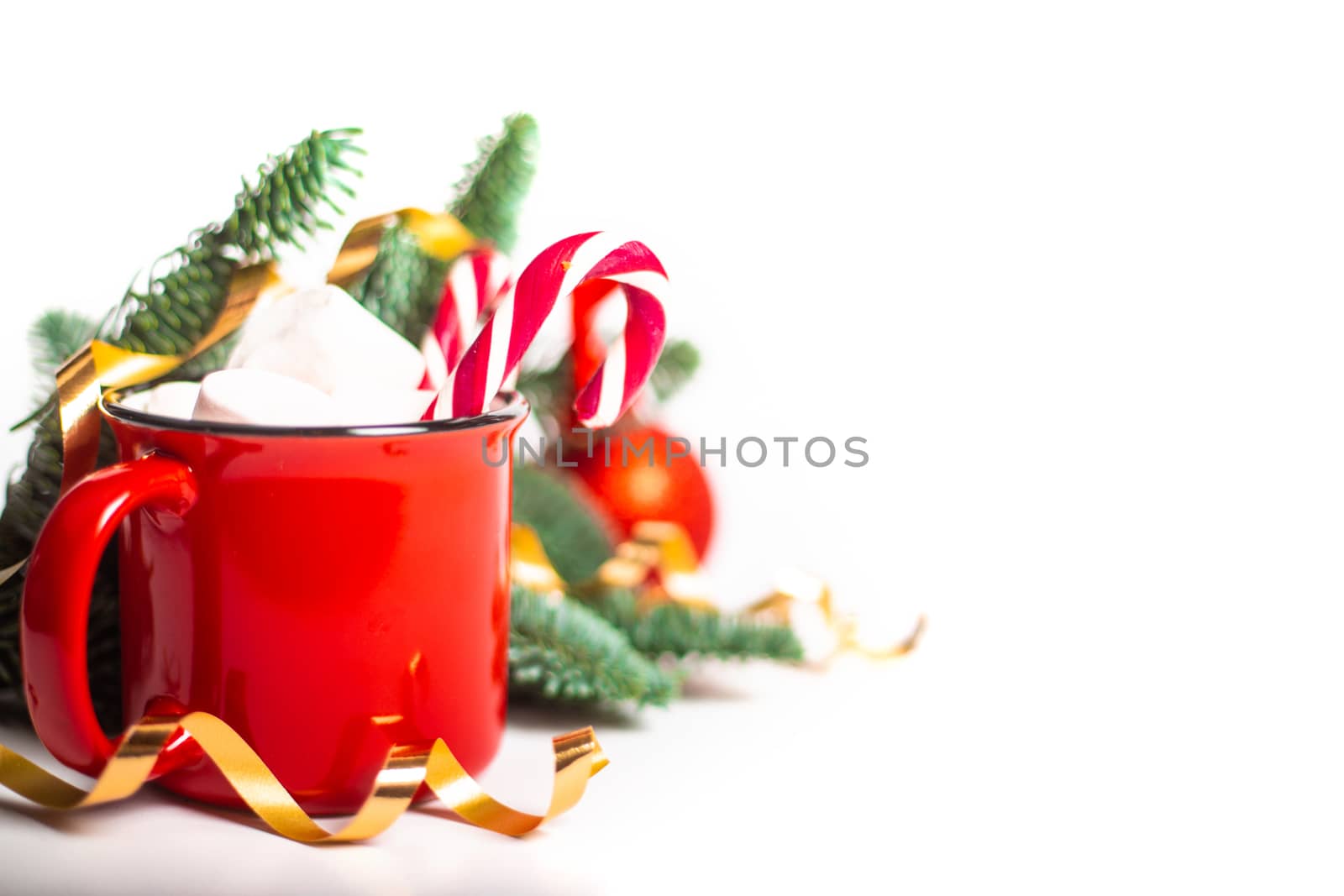 Cocoa in red mug with marshmallows and candy cane and fir tree branches and red and golden baubles and stars isolated on white background