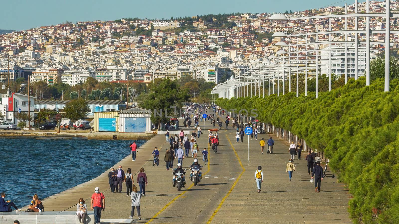 Unidentified persons with face protection walk on the pedestrian area of the city waterfront in Thessaloniki, Greece.