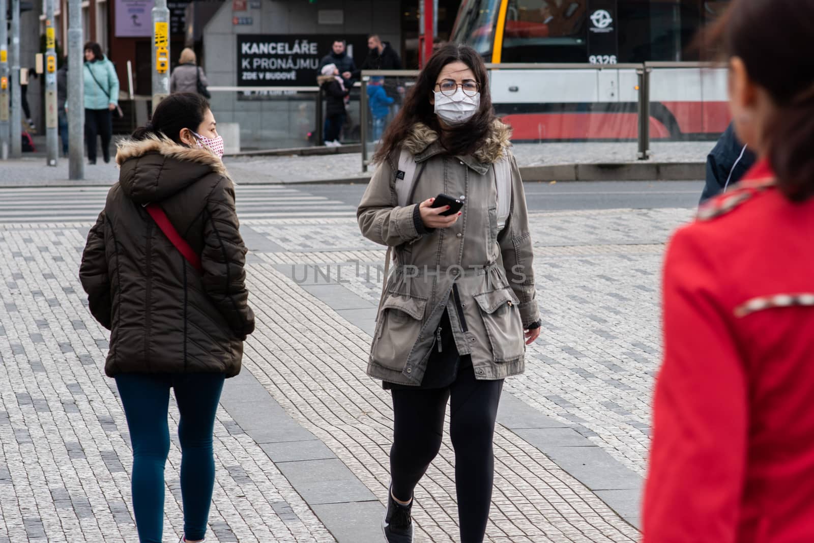 11/16/2020. Prague. Czech Republic. A woman wearing a mask is crossing the railways at Hradcanska tram stop during quarantine. This is a lockdown period in the Czech Republic due to the increase of COVID-19 infectious in the country. Hradcanska tram stop it is in Prague 6