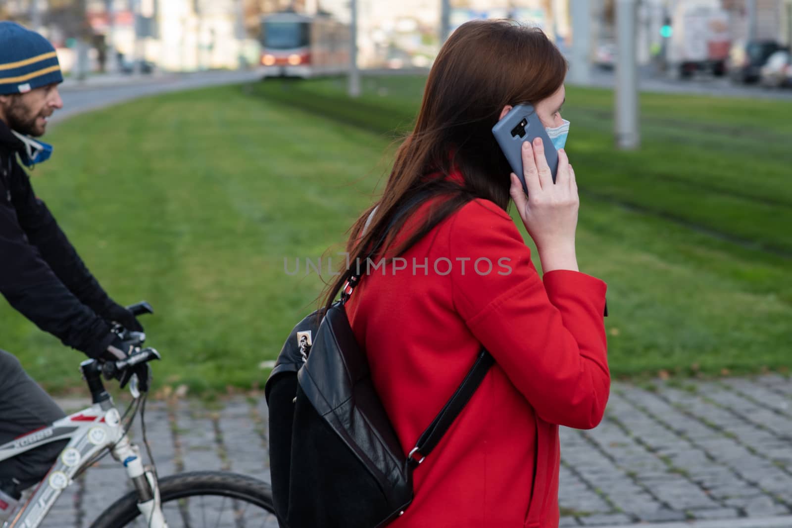 11/16/2020. Prague. Czech Republic. A woman wearing a mask is speaking on her phone while crossing the railways at Hradcanska tram stop during quarantine. by gonzalobell