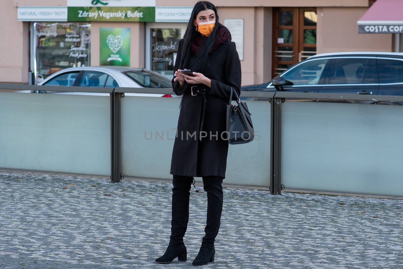 11/16/2020. Czech Republic. A woman wearing a mask is waiting for a tram at Hradcanska tram stop during quarantine. This is a lockdown period in the Czech Republic due to the increase of COVID-19 infectious in the country. Hradcanska tram stop it is in Prague 6