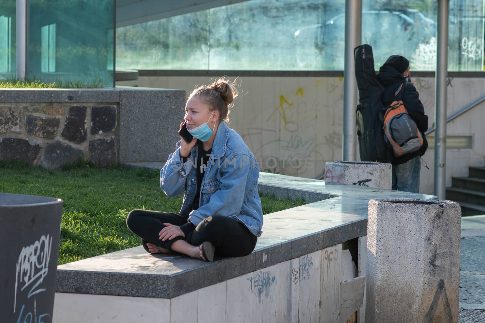 A young woman is talking on her phone close to Hradcanska tram stop during quarantine by gonzalobell