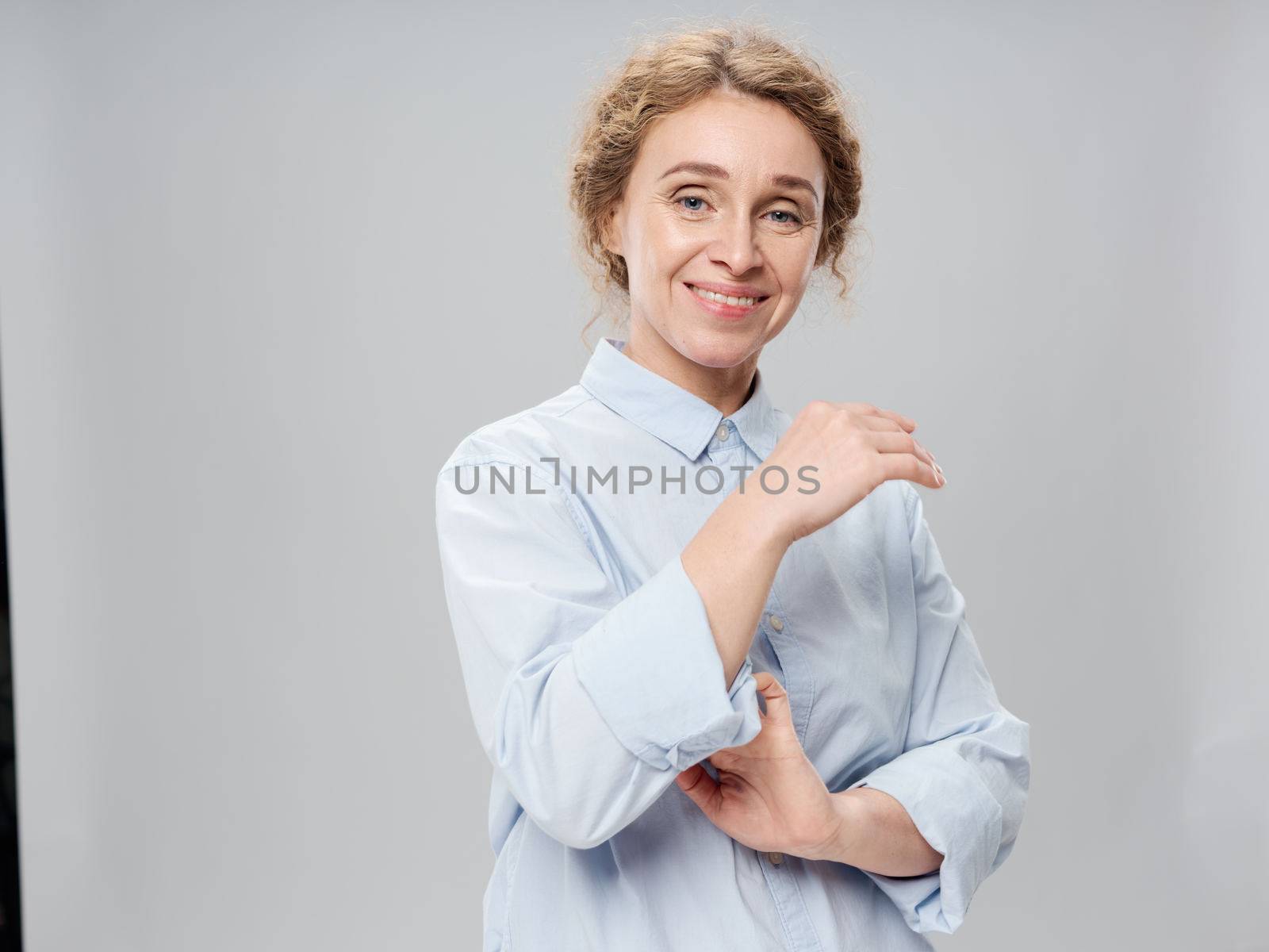 Elderly woman in a light shirt on a gray background smiling at the camera portrait